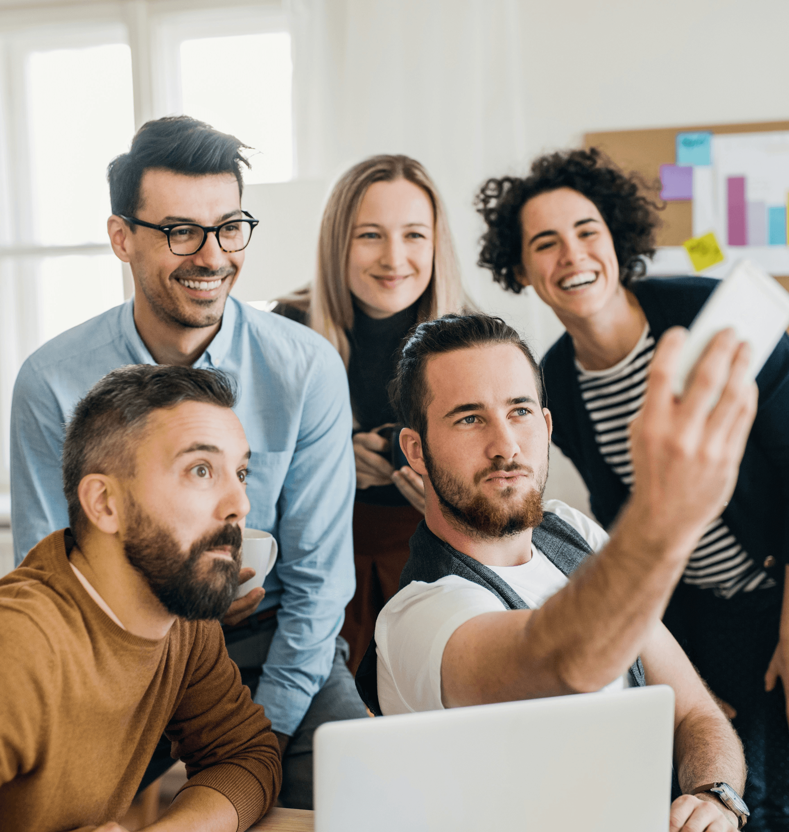 Group of smiling colleagues taking a group selfie.