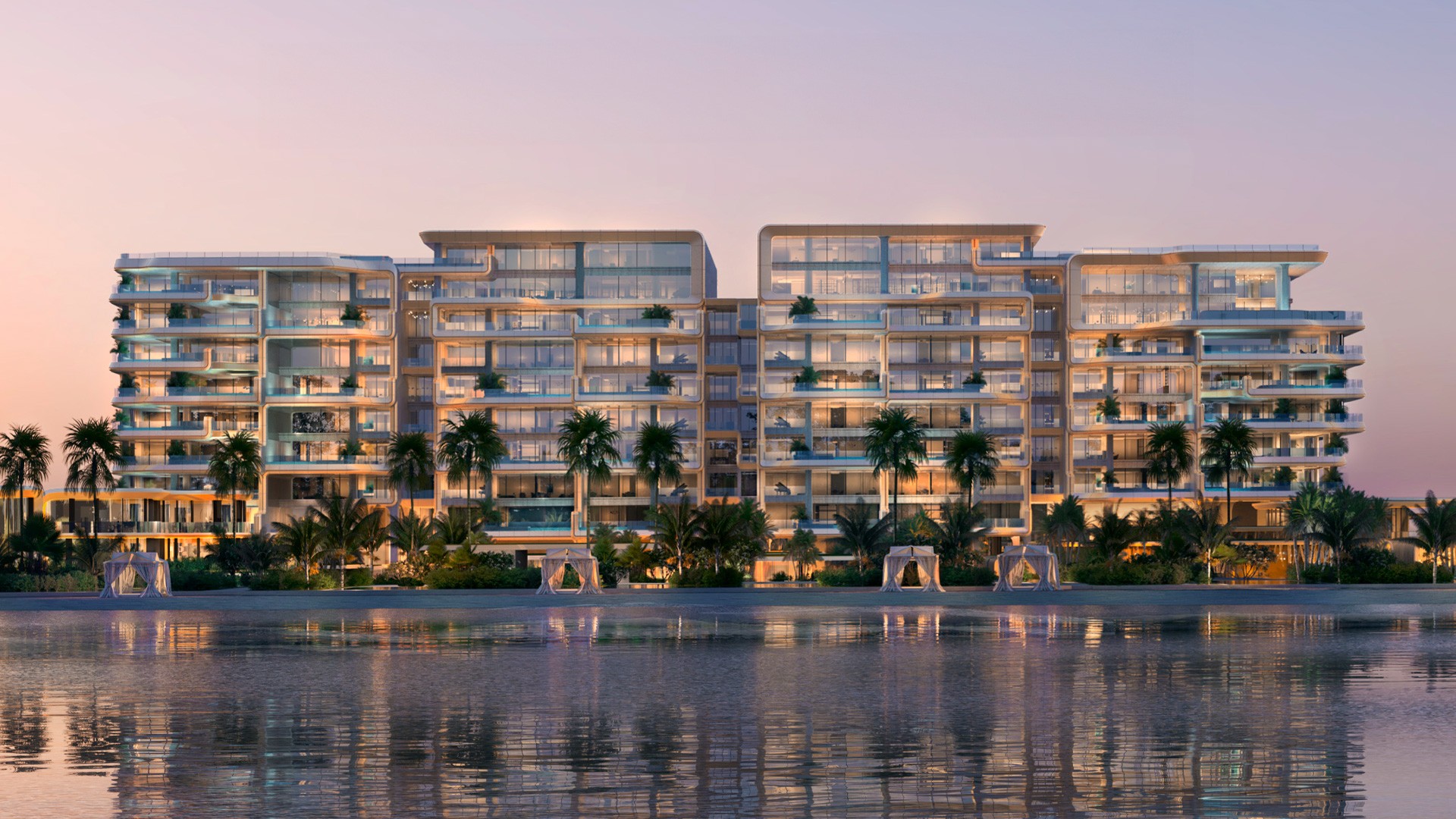 Sunset view of "Enara by Omniyat," a beachfront apartment complex, with the sky painted in shades of orange and pink.