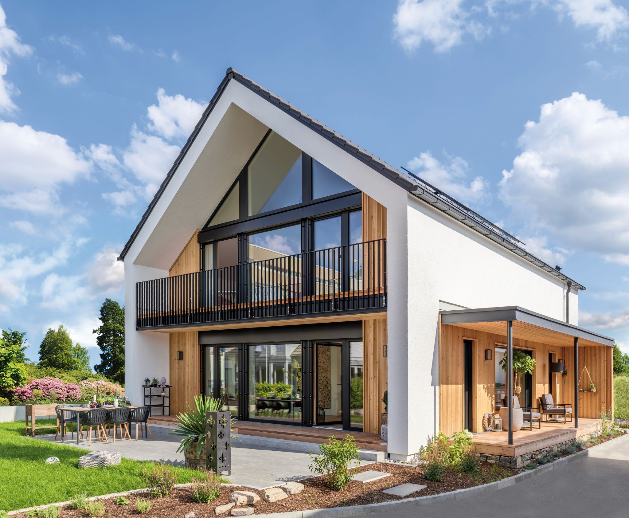 Modernes Einfamilienhaus mit Pultdach, viel Holz und großen Glasflächen, Terrasse und Außenbestuhlung.
