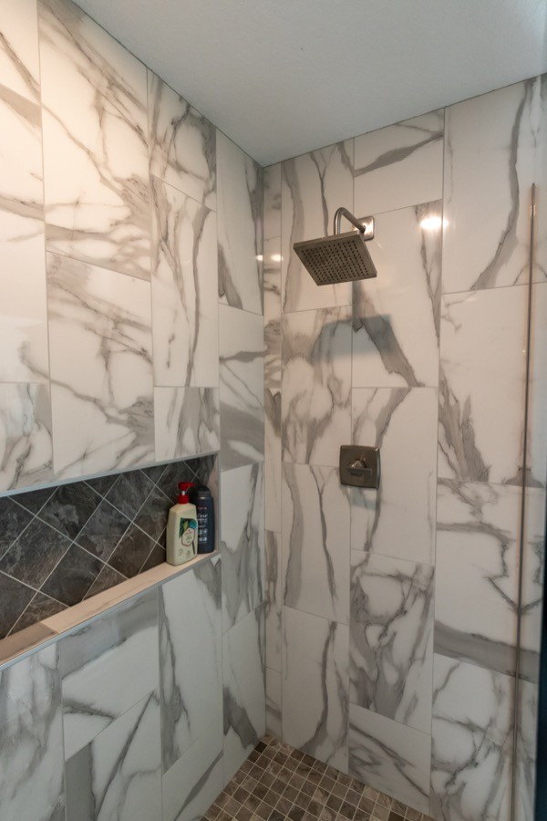 Large white tiled shower and ledge with backsplash