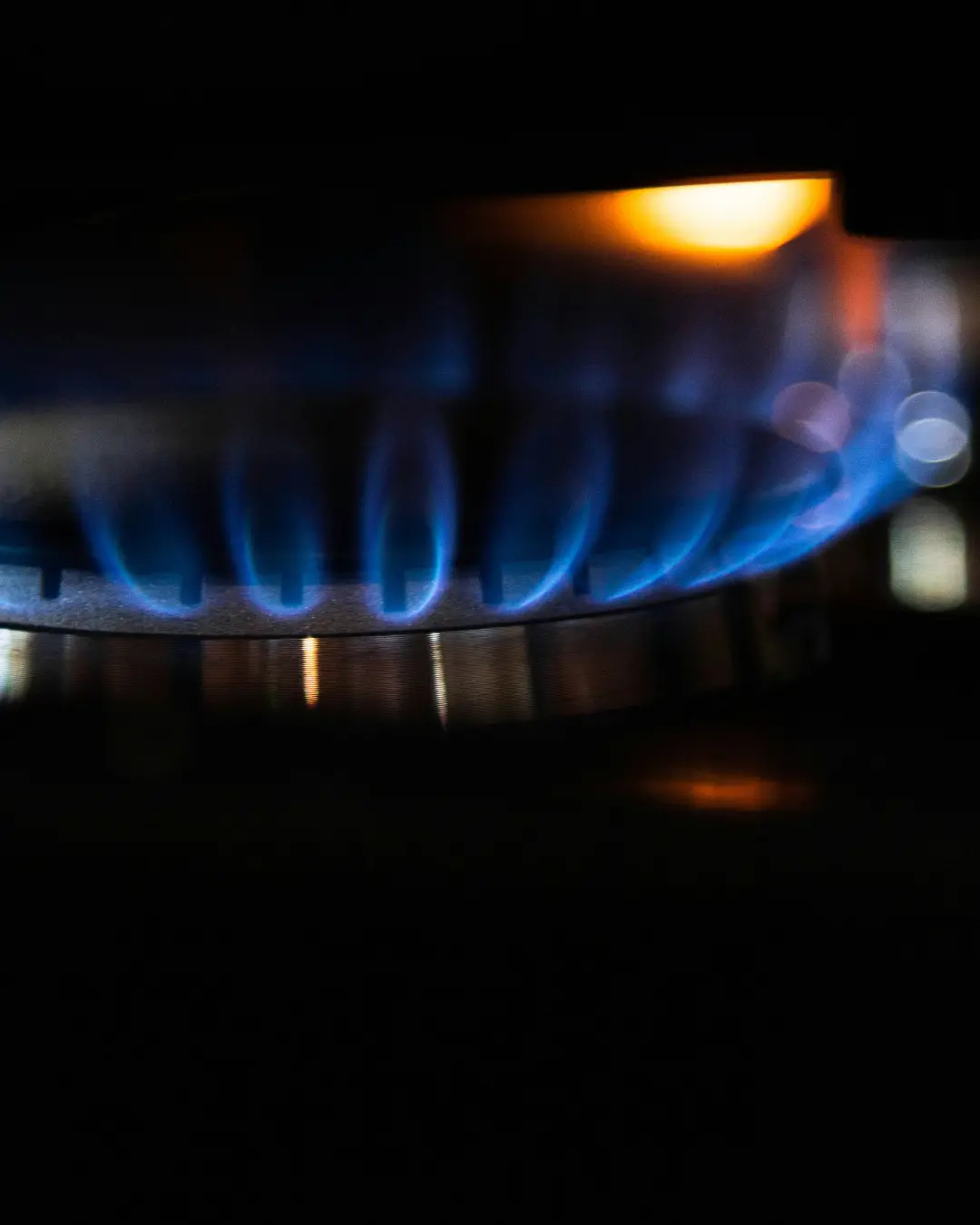 A smiling woman with her arms crossed, standing against a dark green background. She has long, dark hair.