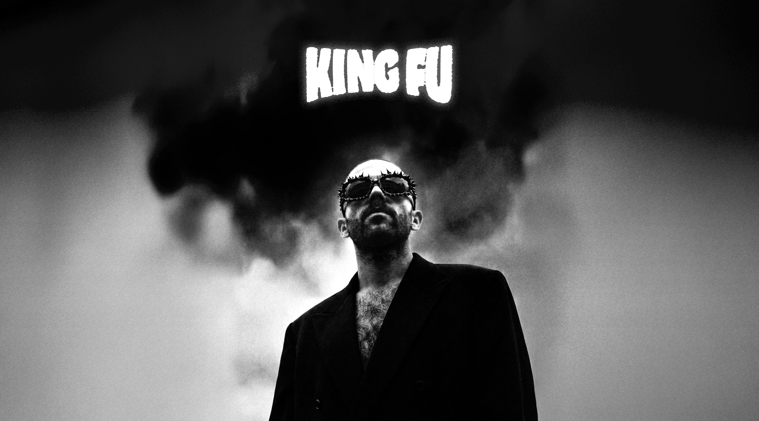 An indoor exhibition space with various artist booths at the Herofest convention in Bern. The booth in the centre of the image is the one of Loveboy and His Imaginary Friends. It features framed artworks, posters, and a small seating area with vintage televisions and inflatable palm trees. Another booth in the background, labeled 'Midnight Spells,' displays gothic-themed merchandise. The space has an industrial ceiling with exposed metal beams and bright overhead lighting, creating a creative and eclectic atmosphere.