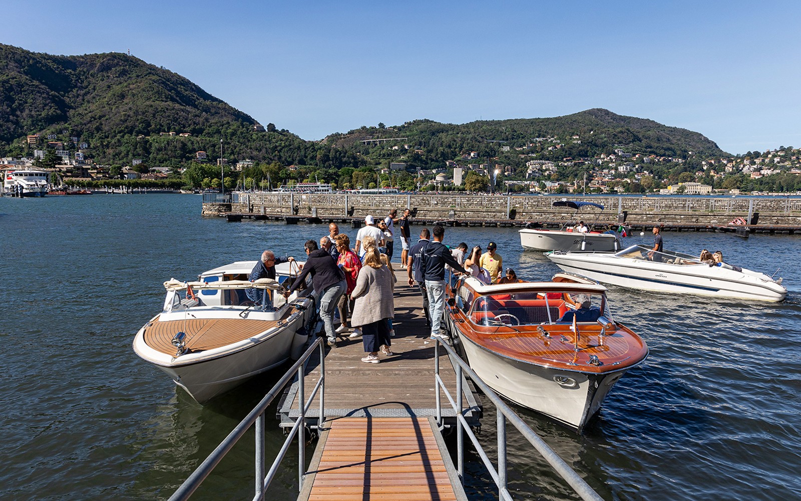 游客在科莫湖码头登船，背景是群山。