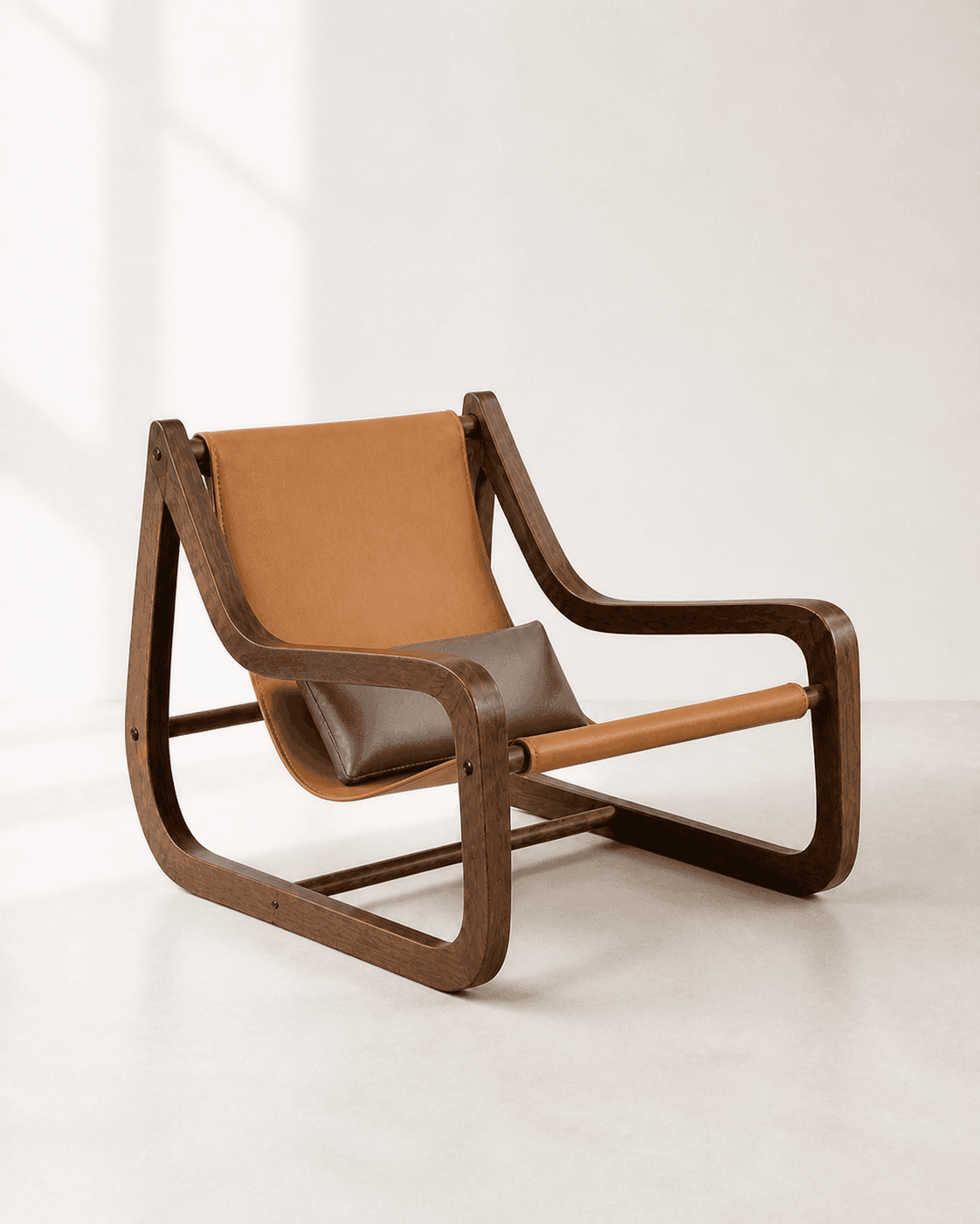 Alternative three-quarter view of Nera Lounge Chair, showing a walnut loop frame with a saddle-tan leather sling and warm-grey cushion