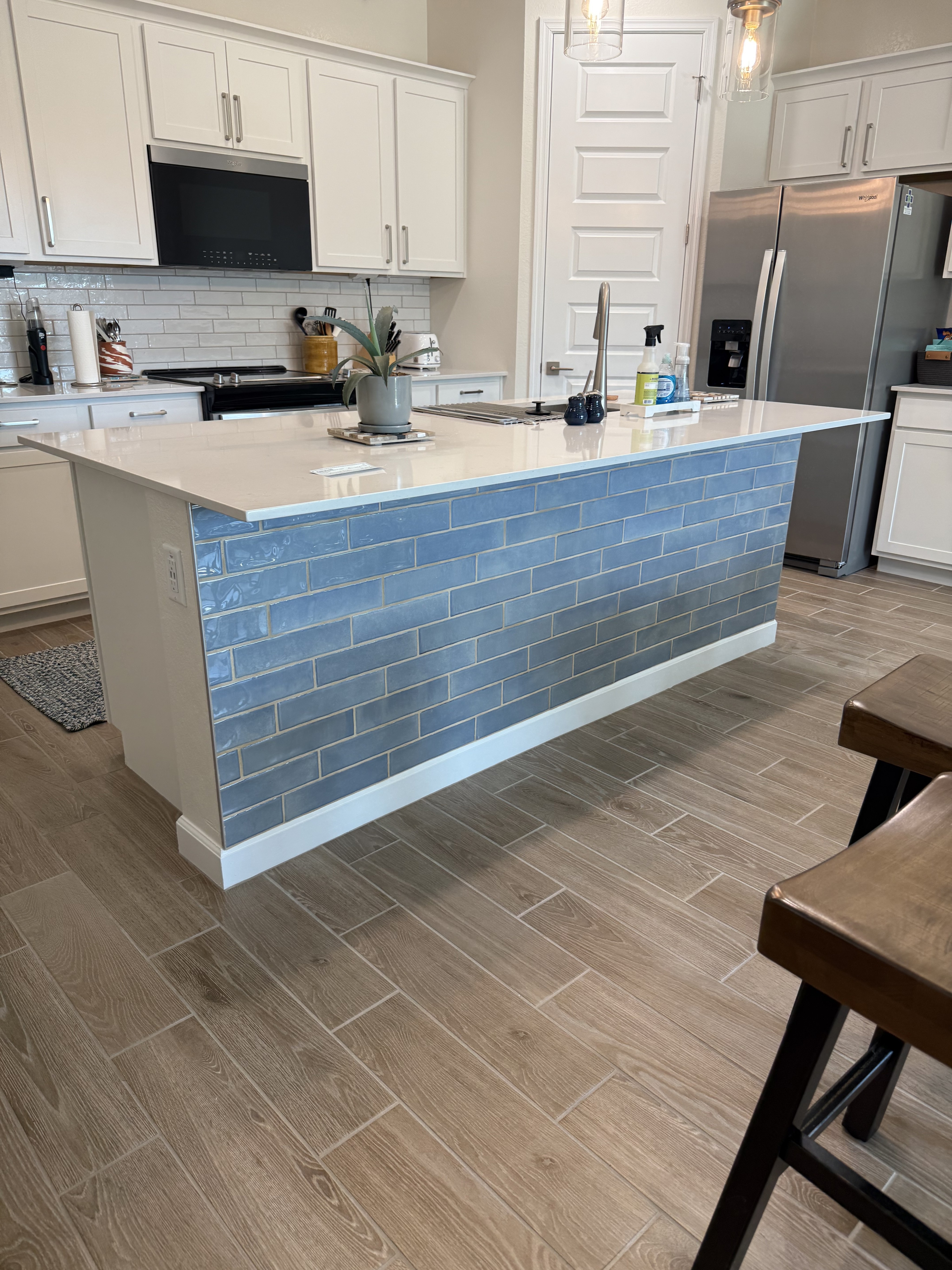 Stylish kitchen with a white countertop, under-cabinet lighting, and a hexagonal tile backsplash.