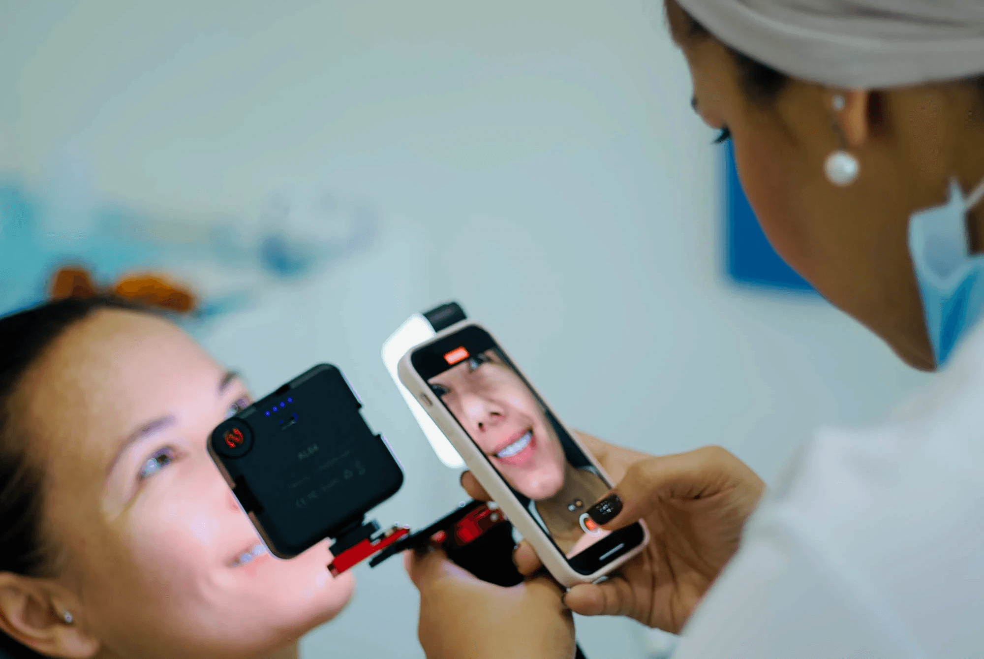 A woman taking a picture of a patient with her white teeth after having a Hollywood smile treatment with Invisalign Center