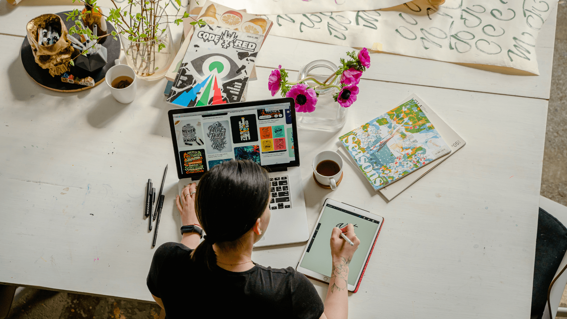 A woman working on a laptop and sketching on a tablet