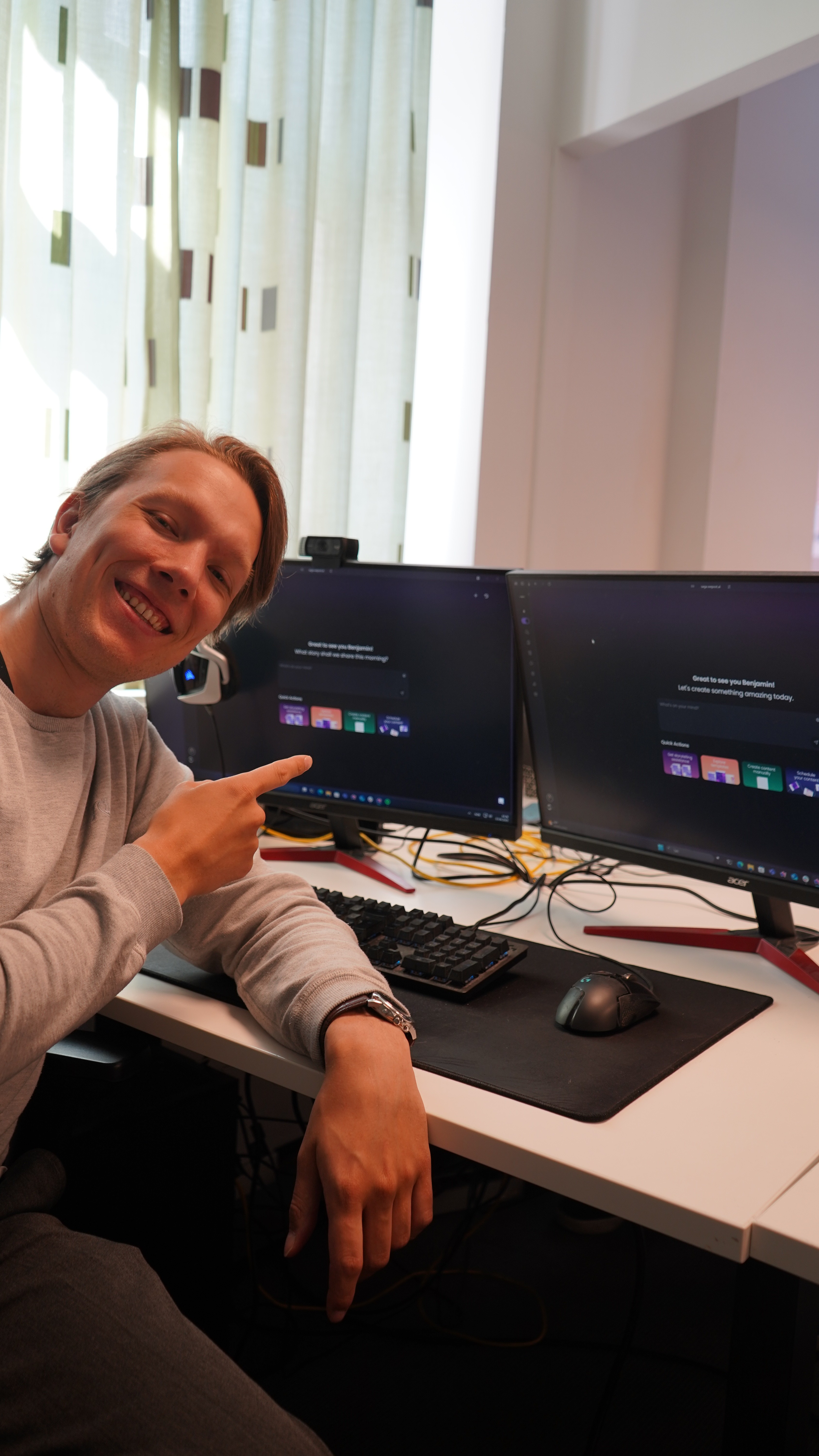 Smiling young man with short hair poses against a dark background, wearing a green button-up shirt.