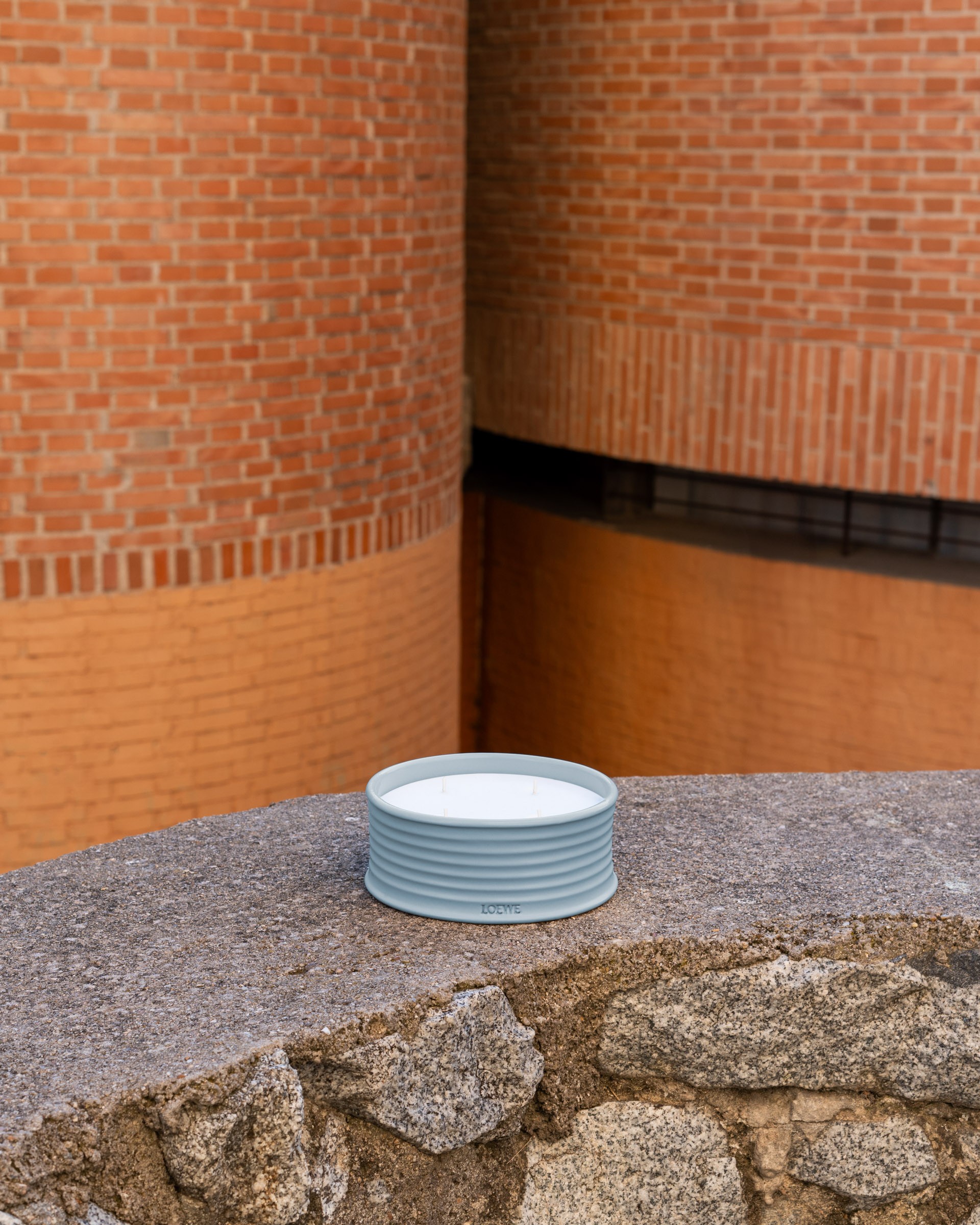 LOEWE candle photographed against brickwork and stone at Los Círculos de Oíza