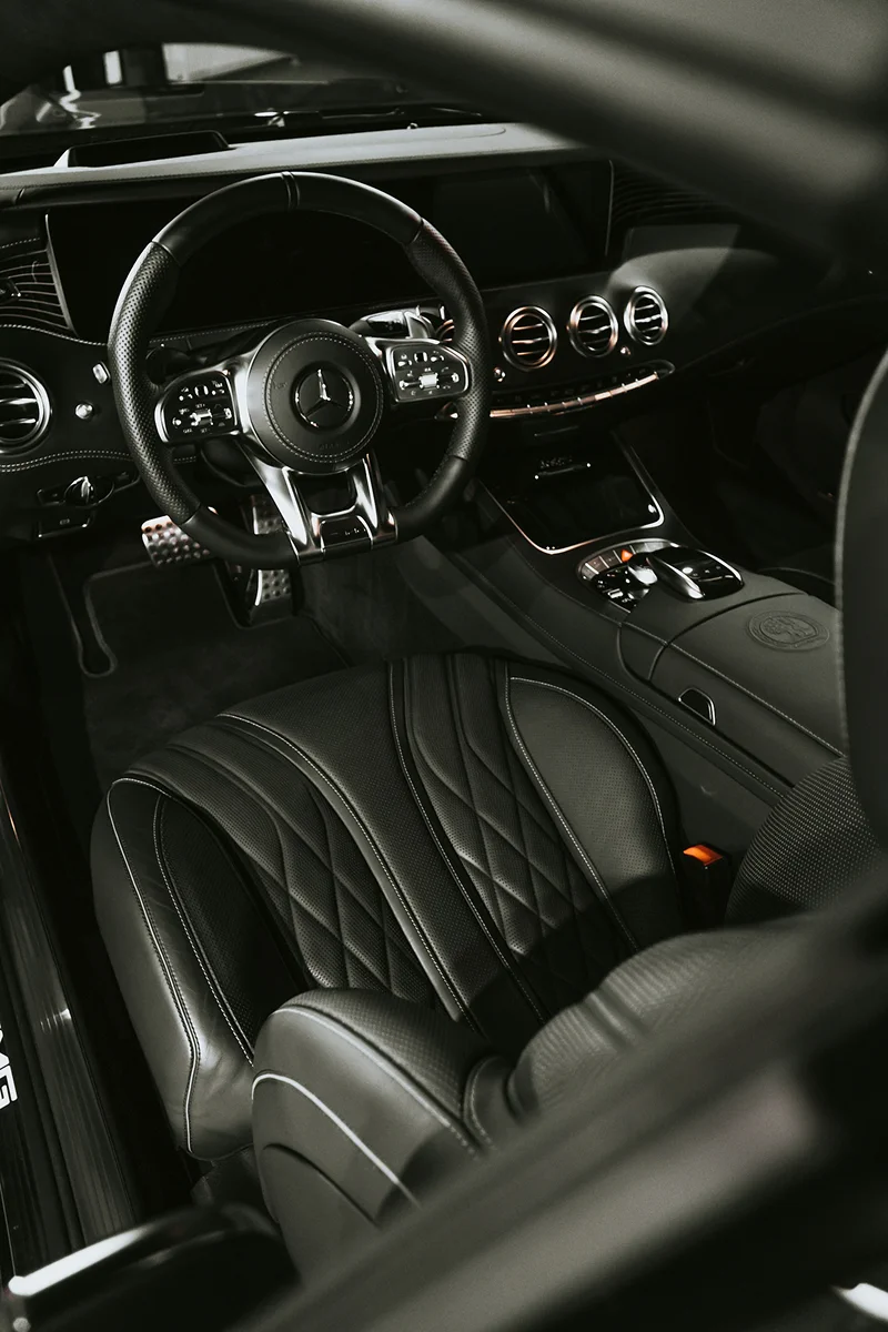 Luxury vehicle interior with clean leather seats, steering wheel, and premium cabin detailing.