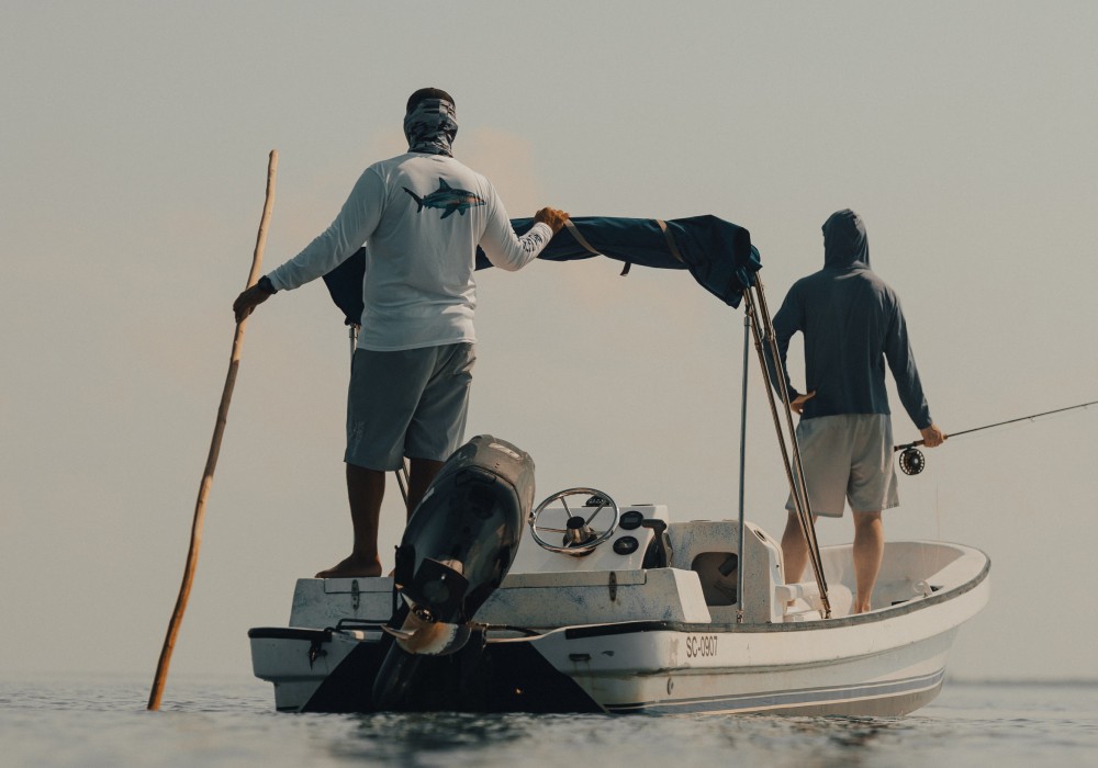 Marlon Leslie poling skiff with angler on bow in southern Belize
