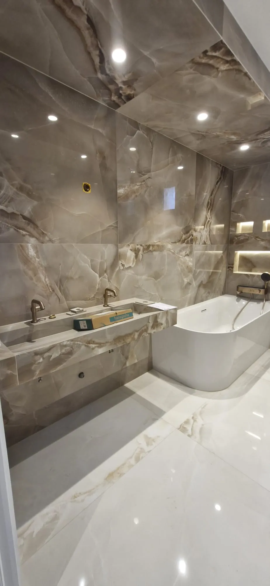 Salle de bain carrelée en grand format effet marbre autour d'une baignoire îlot