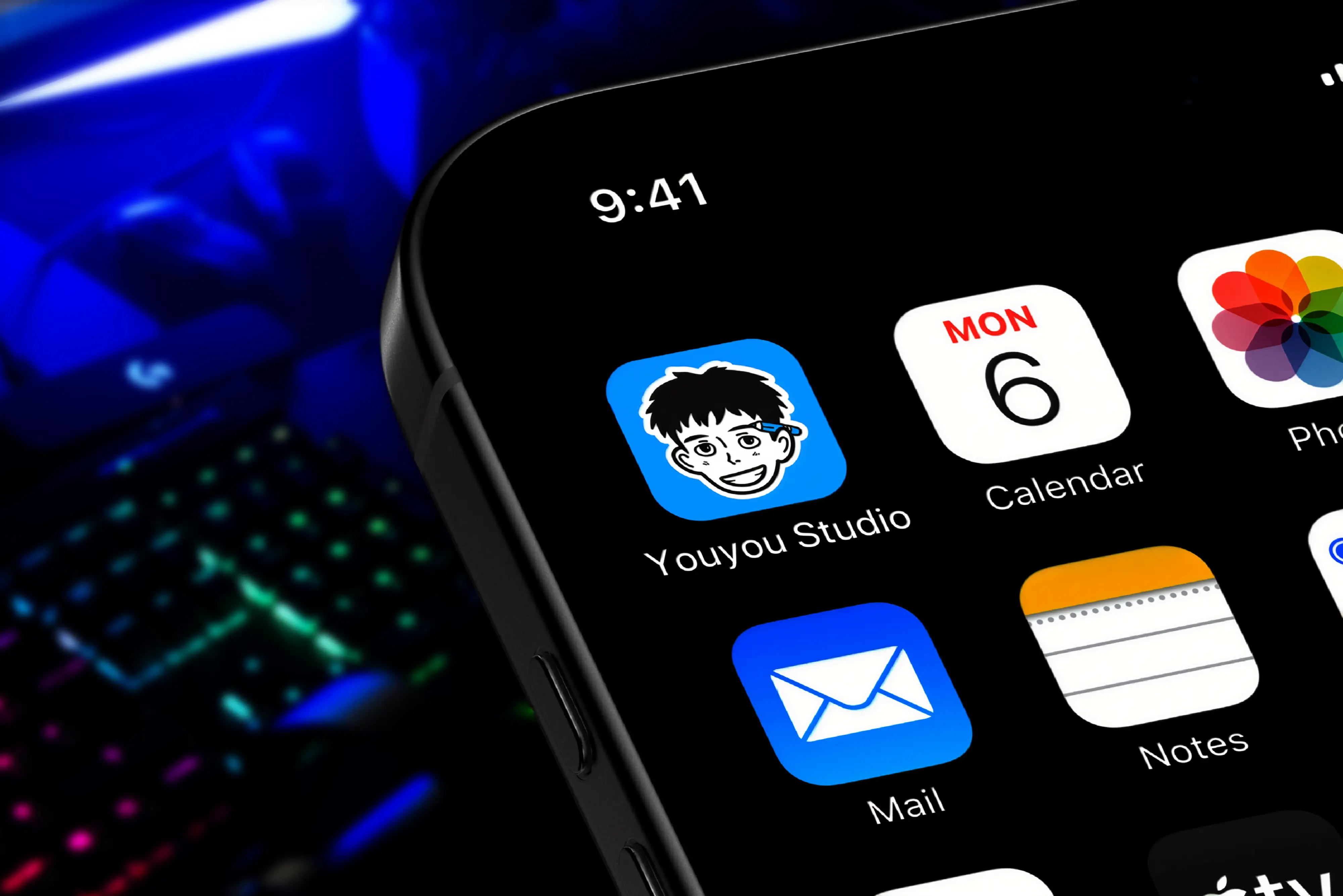 Mockup iPhone affichant l'icône d'application Youyou Studio avec la mascotte sur fond jaune parmi d'autres apps