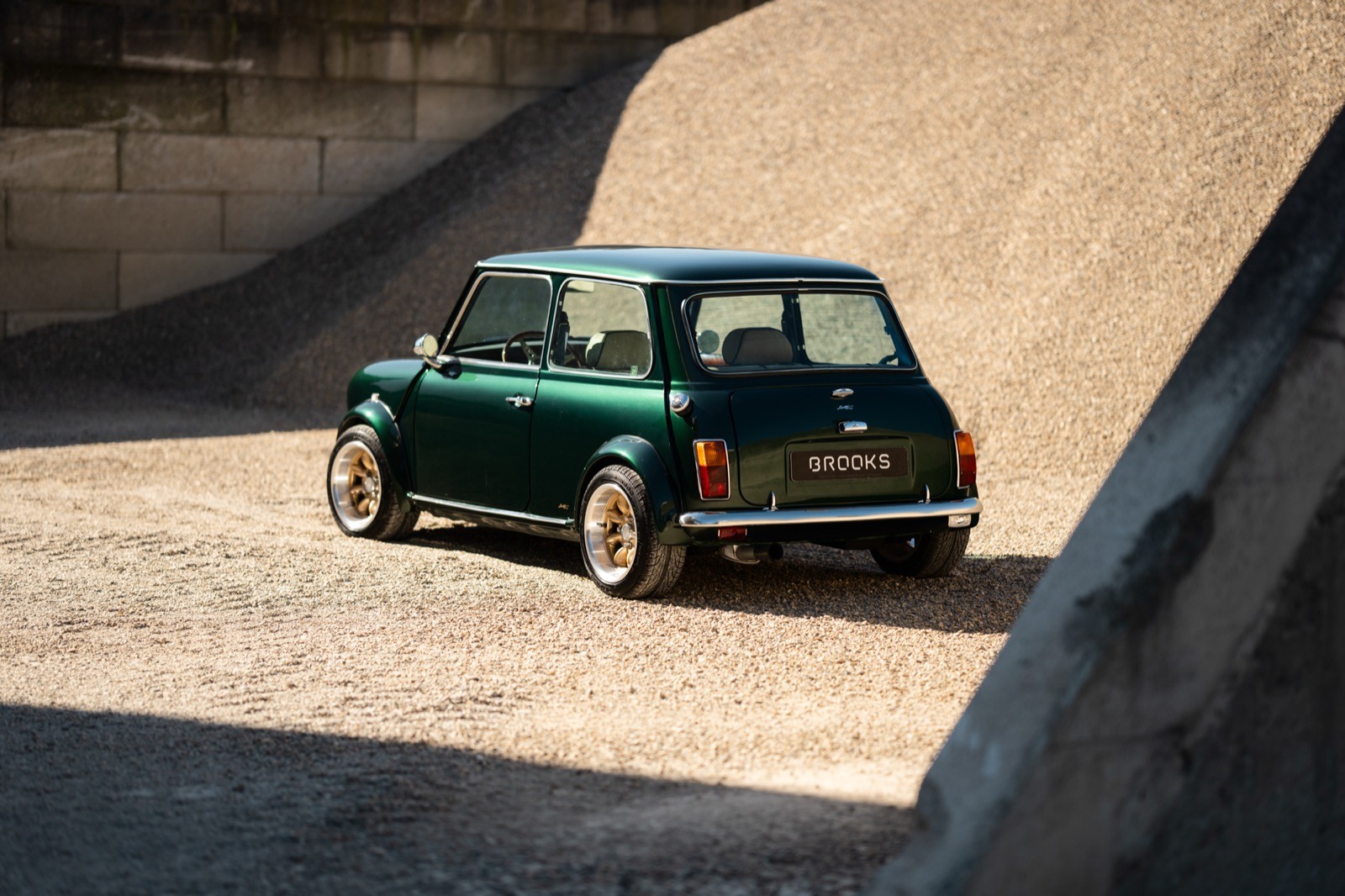 A small, green and black vehicle parked on a sandy surface, with a warm sunset lighting the scene.