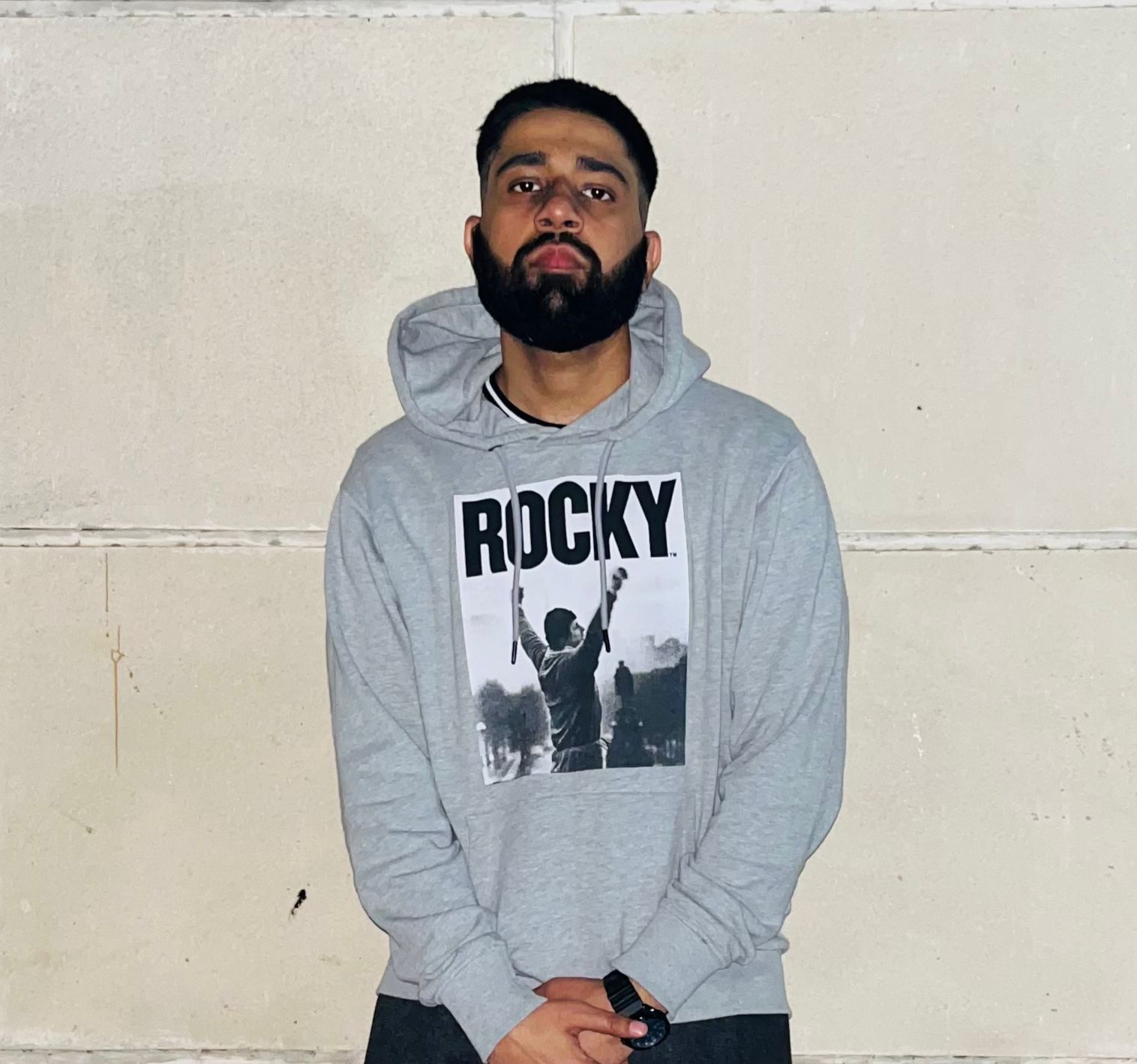 a man wearing glasses and a blazer with a lighting that casts a soft shadow on the wall behind him