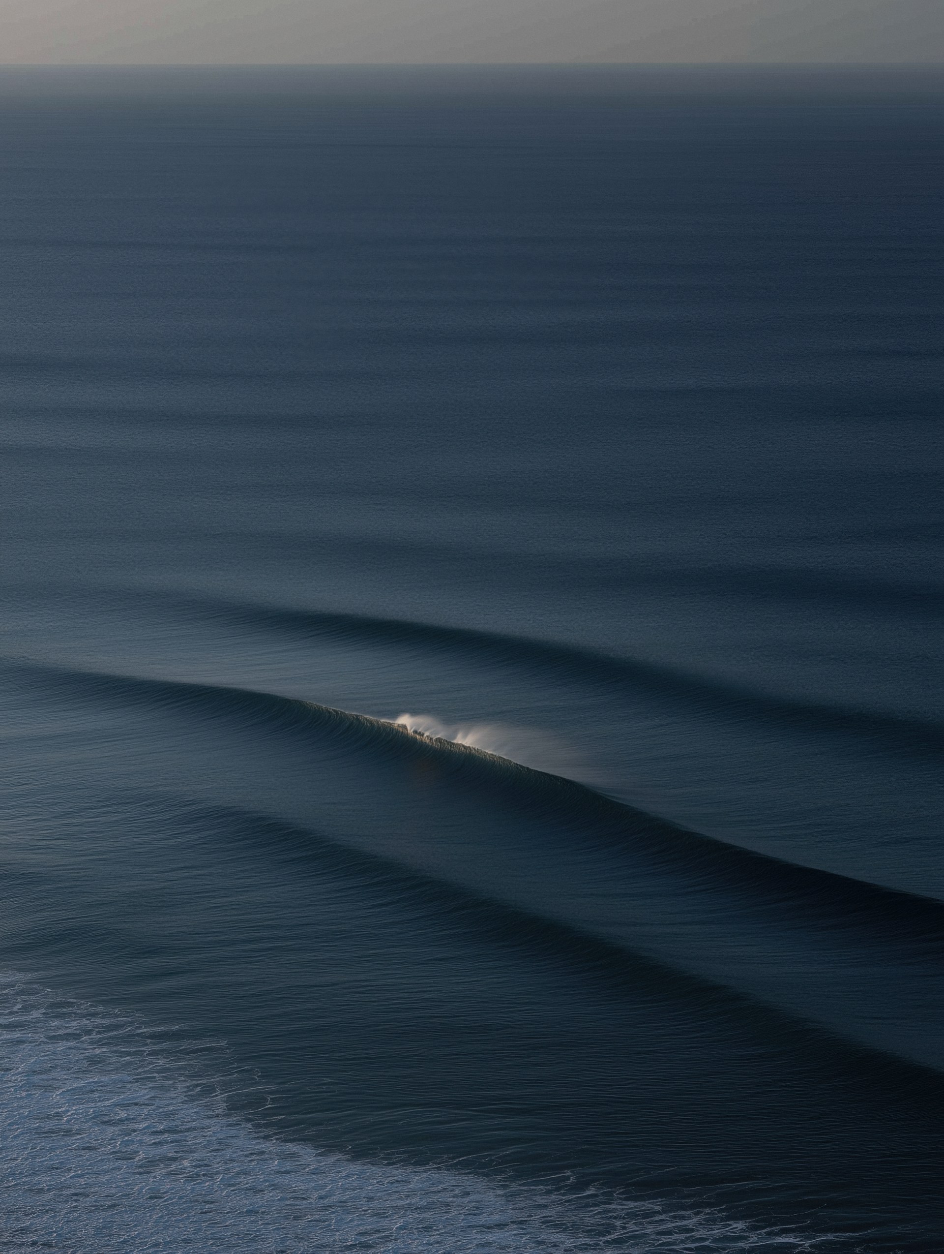 Long swell lines on a dark sea at dusk