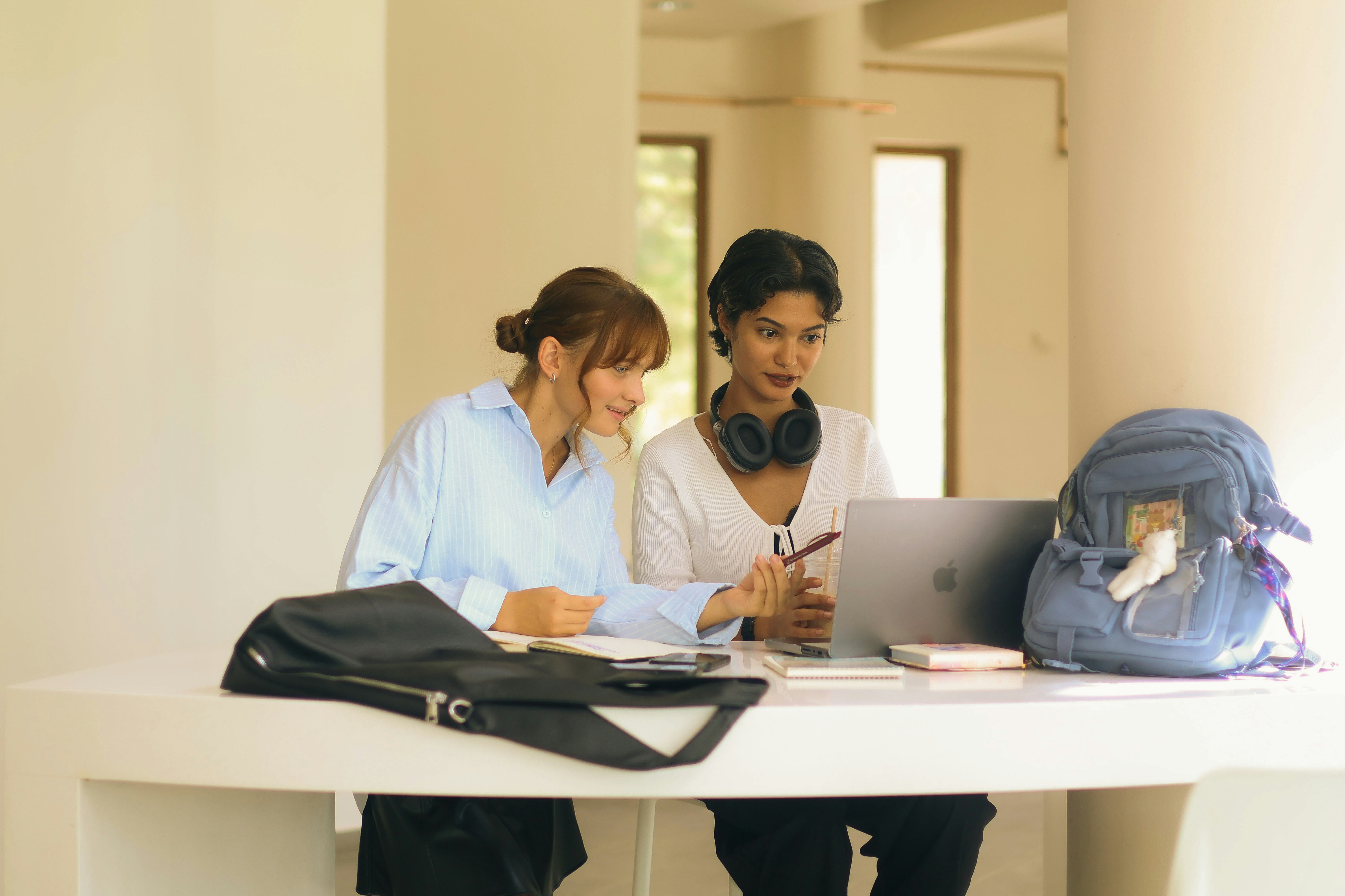 Two women studying together at a table with laptop.