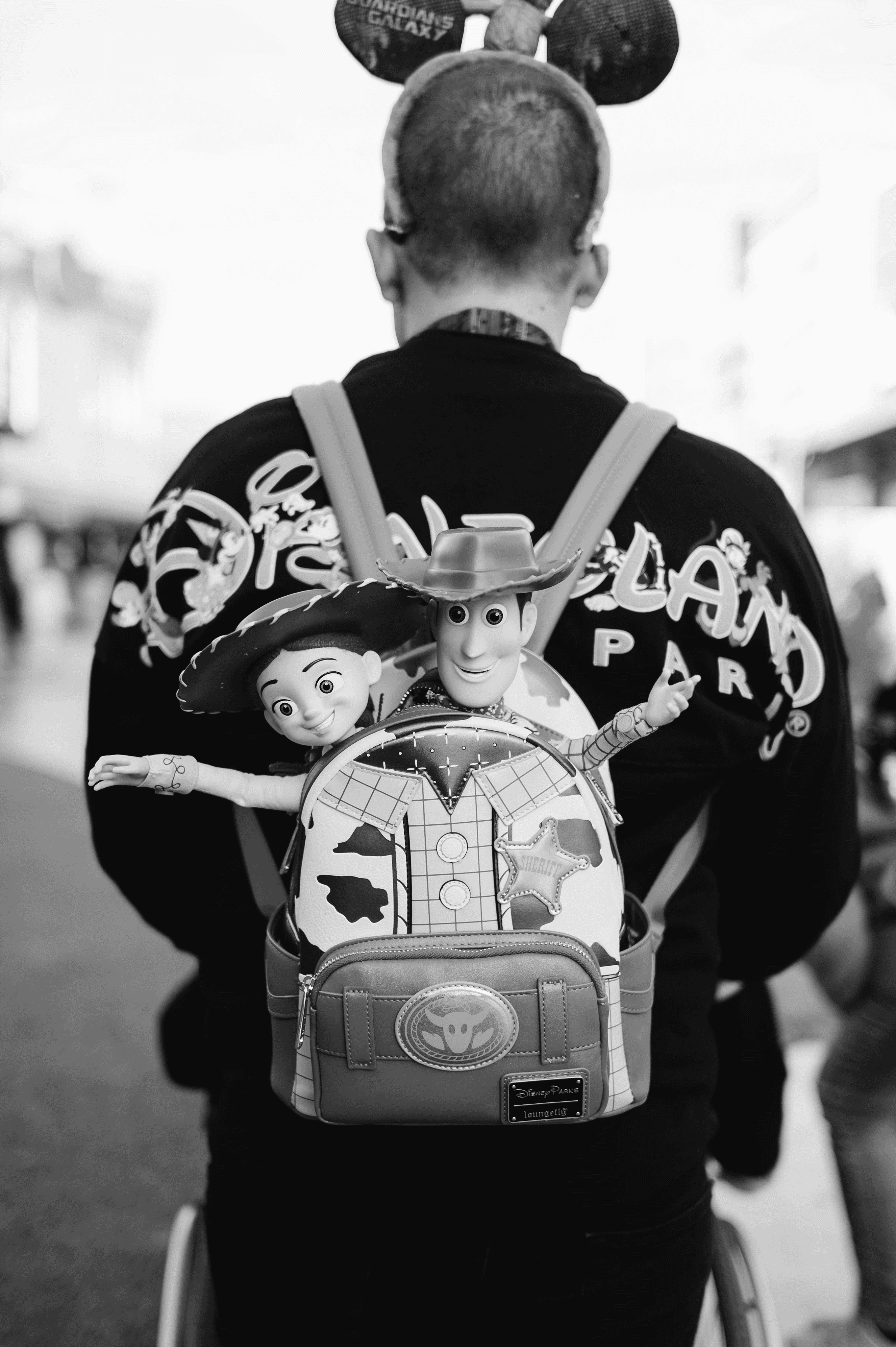 Person wearing toy story backpack and mickey mouse ears
