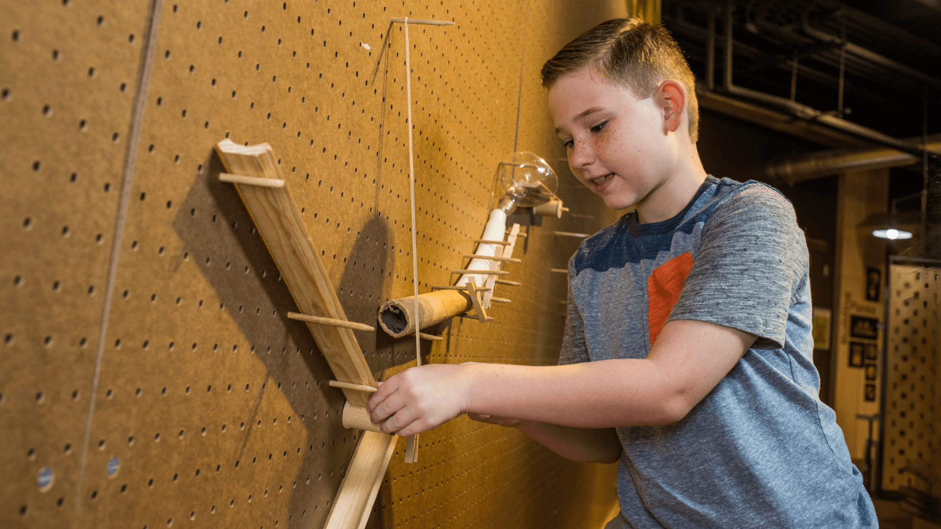 A young boy puts together a ramp to race his marble down.
