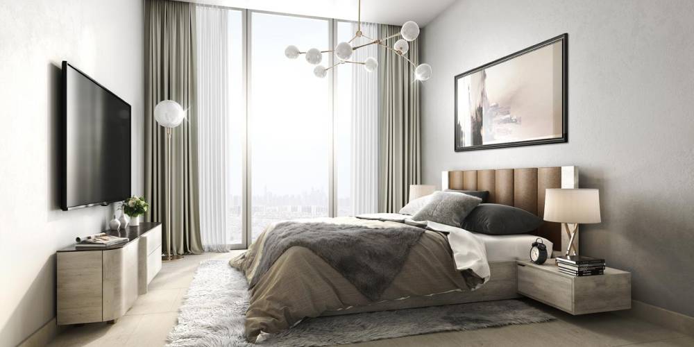 Interior of a contemporary bedroom at Azizi Mirage, showcasing a bed, a desk, and a bright window.