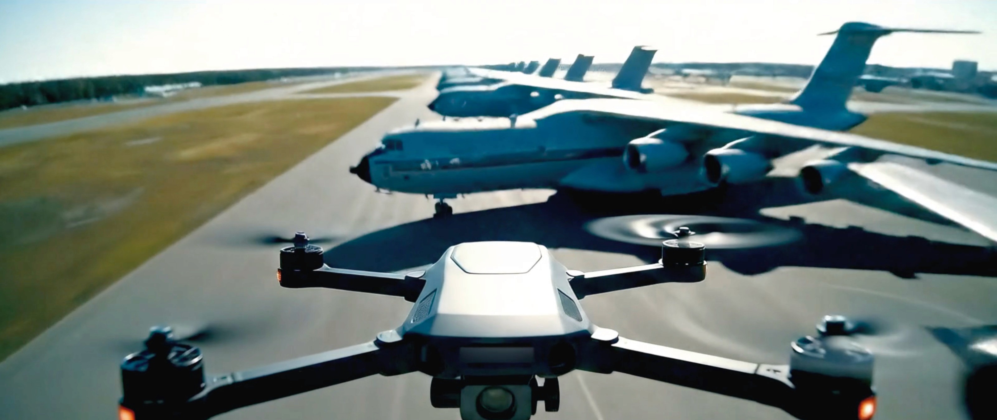 Dynamic AI aerial shot of a drone flying alongside military transport jets with intense action energy.