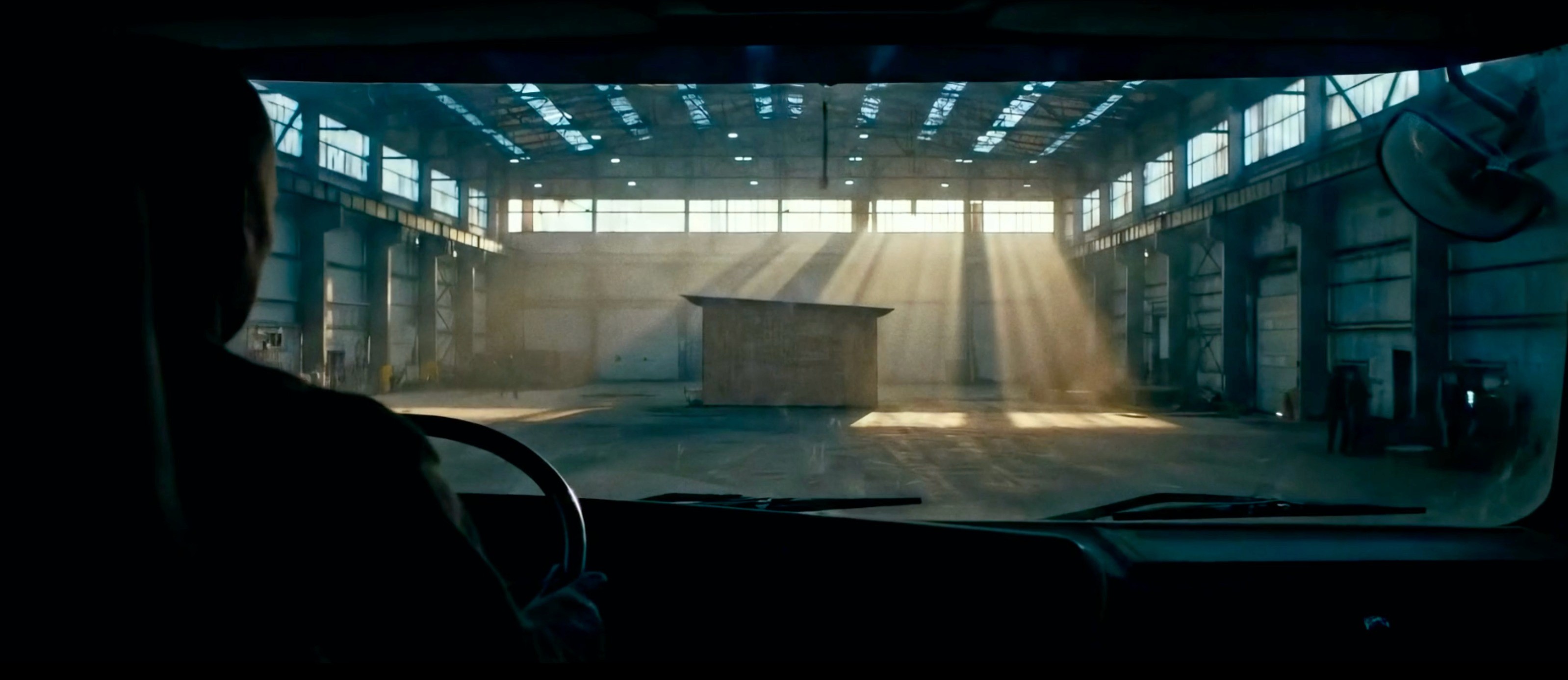 AI-rendered cinematic shot of a warehouse interior with dramatic sunbeams streaming through high windows.