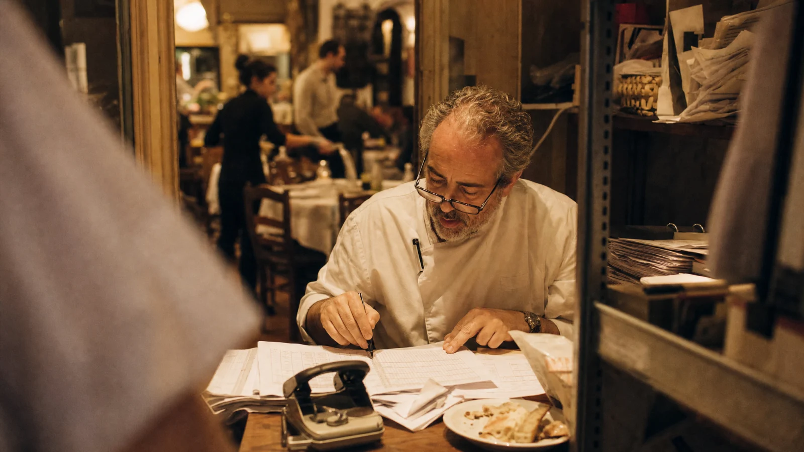 Titolare di trattoria segue con la penna una riga del conto economico stampato a fine serata