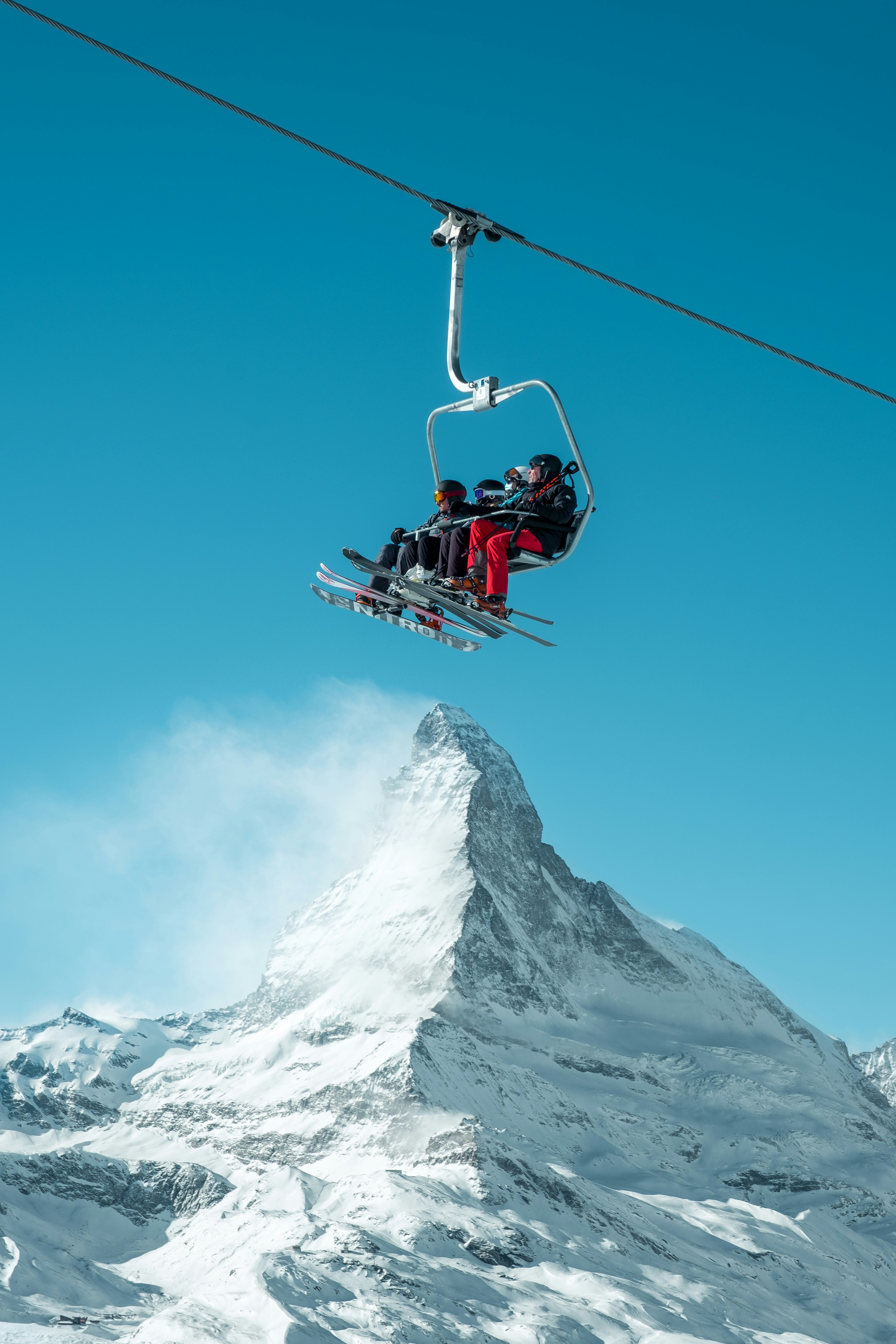red and black cable car over snow covered mountain