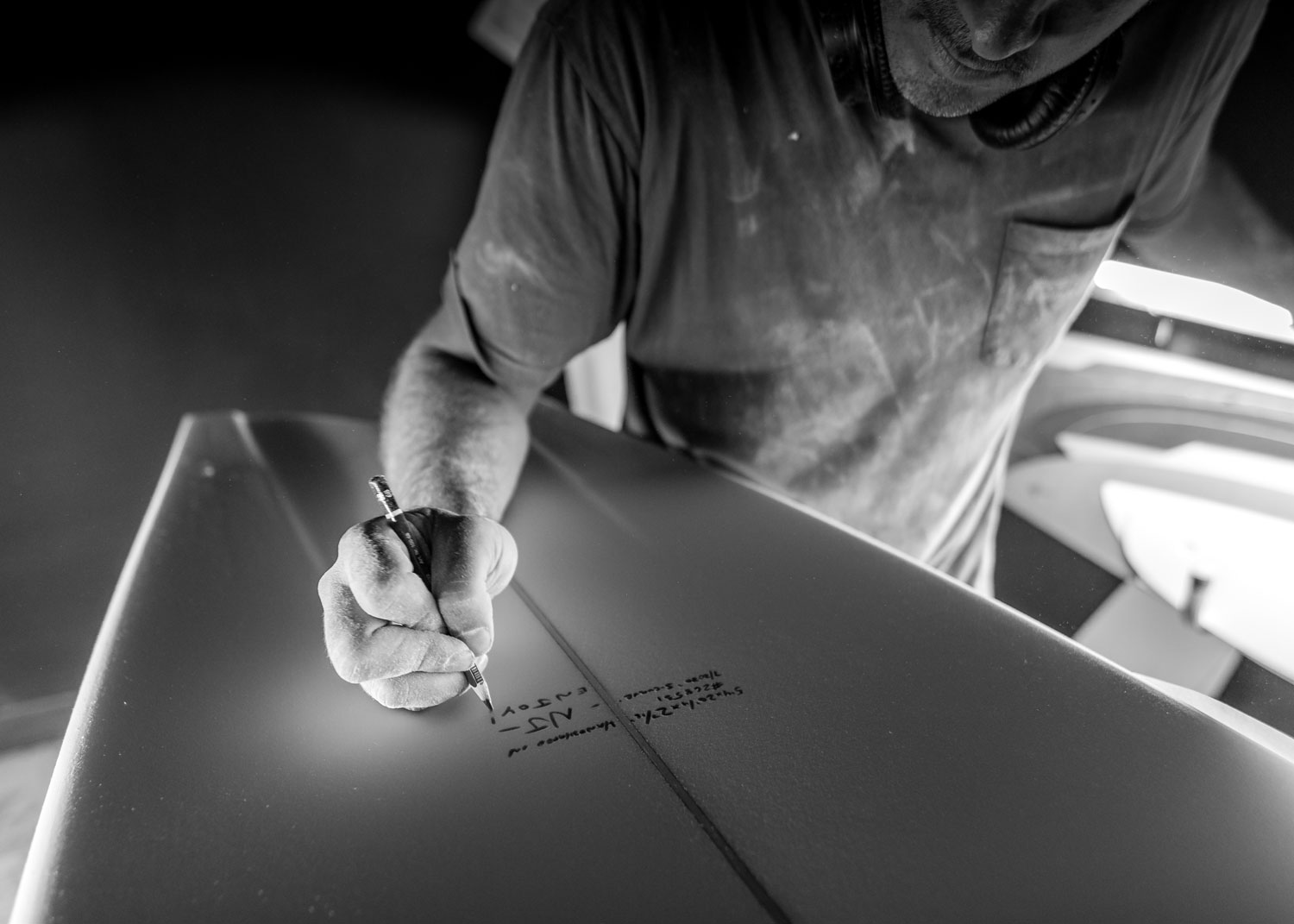 Man writing on a surfboard with a marker.