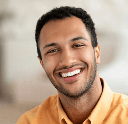 a smiling man sitting on a couch in a living room