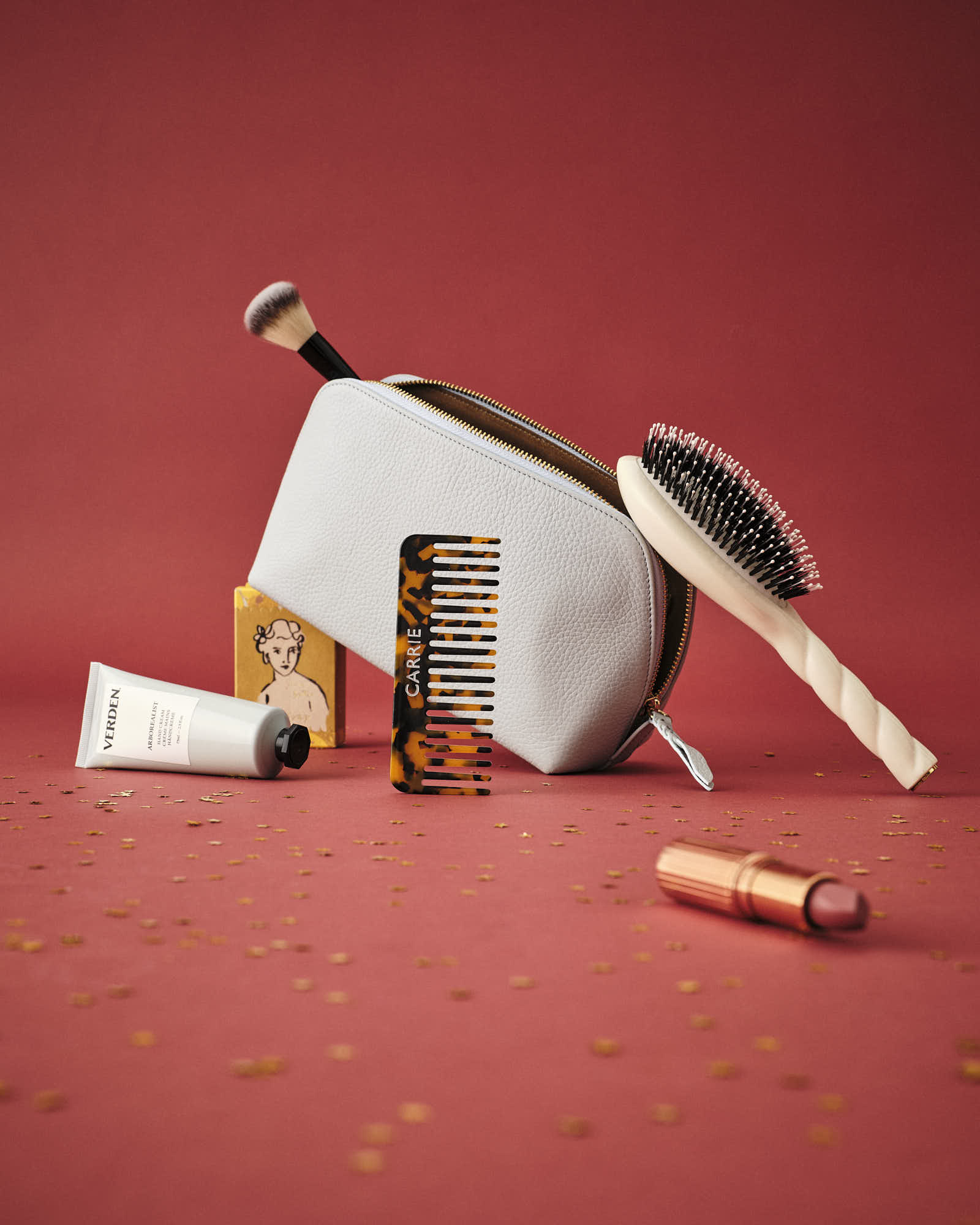Makeup bag with beauty products and accessories on a red background.