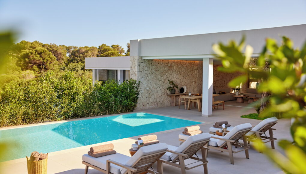 Private Hotelvilla mit eigenem Infinity-Pool, modernen Sonnenliegen und einer überdachten Terrasse mit Natursteinwand, umgeben von mediterraner Vegetation.