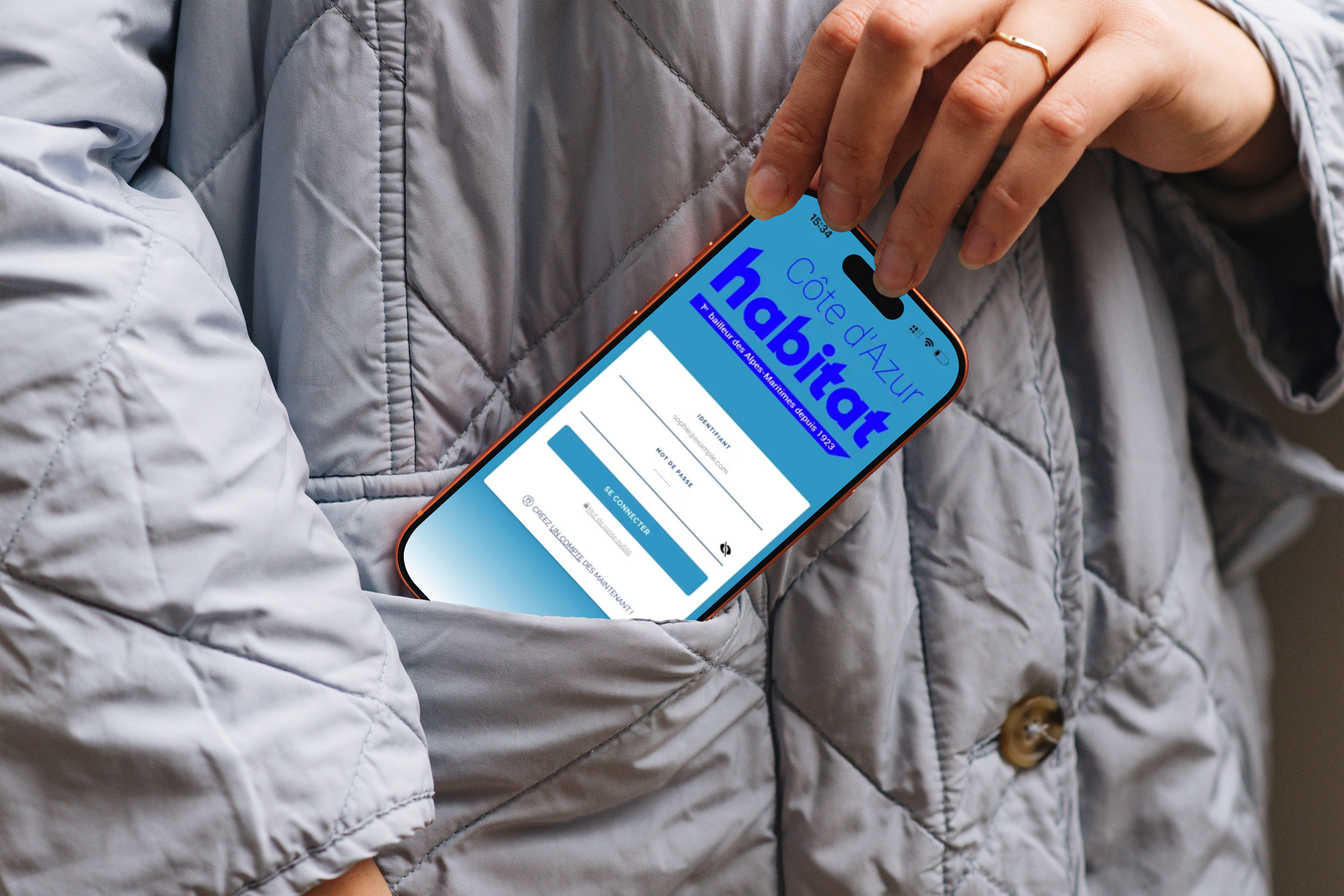 Personne sortant de sa poche un smartphone, sur l'écran on voit que l'application Côte d'Azur Habitat est lancée.