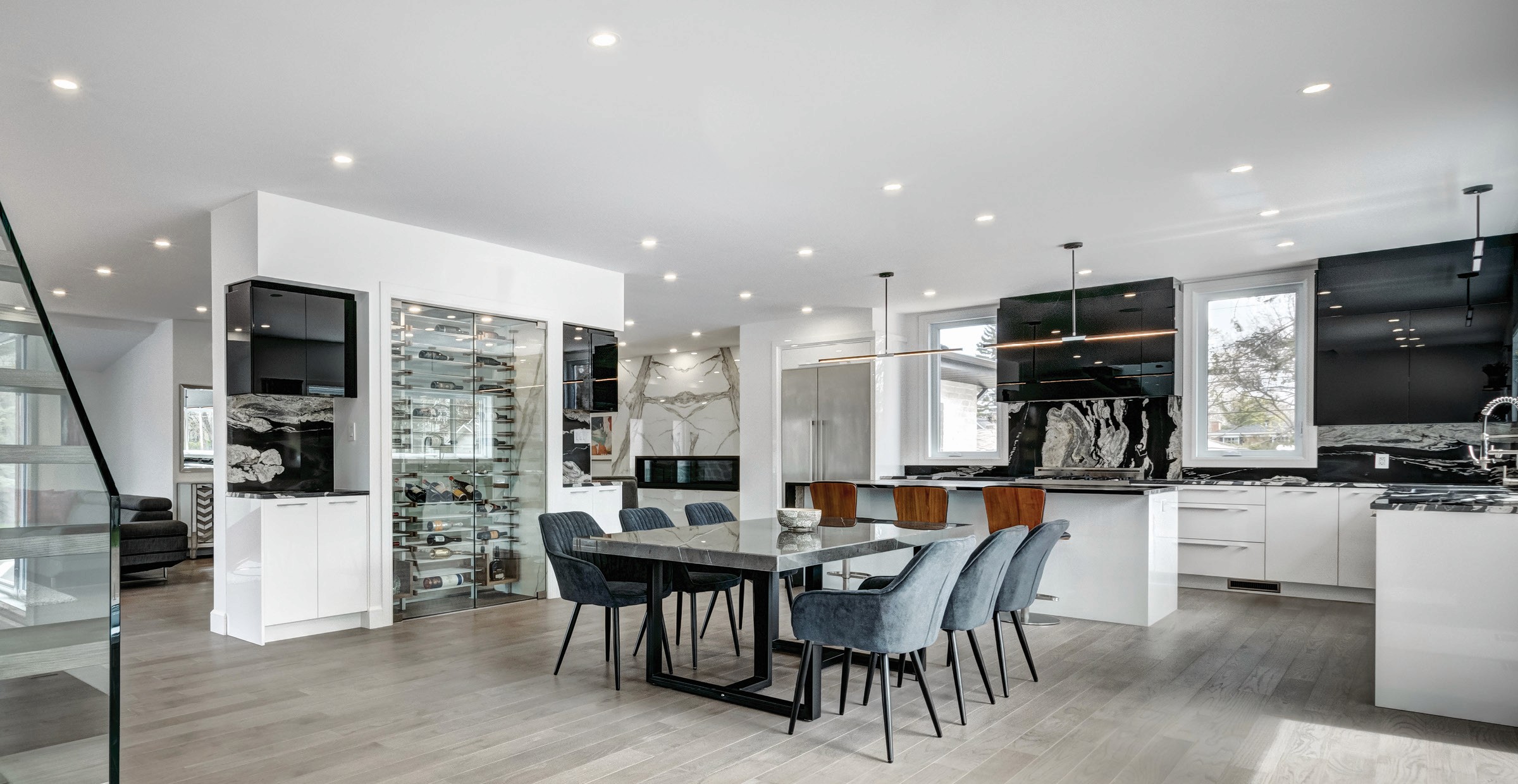 Modern kitchen with dining area, wine display, and fireplace.