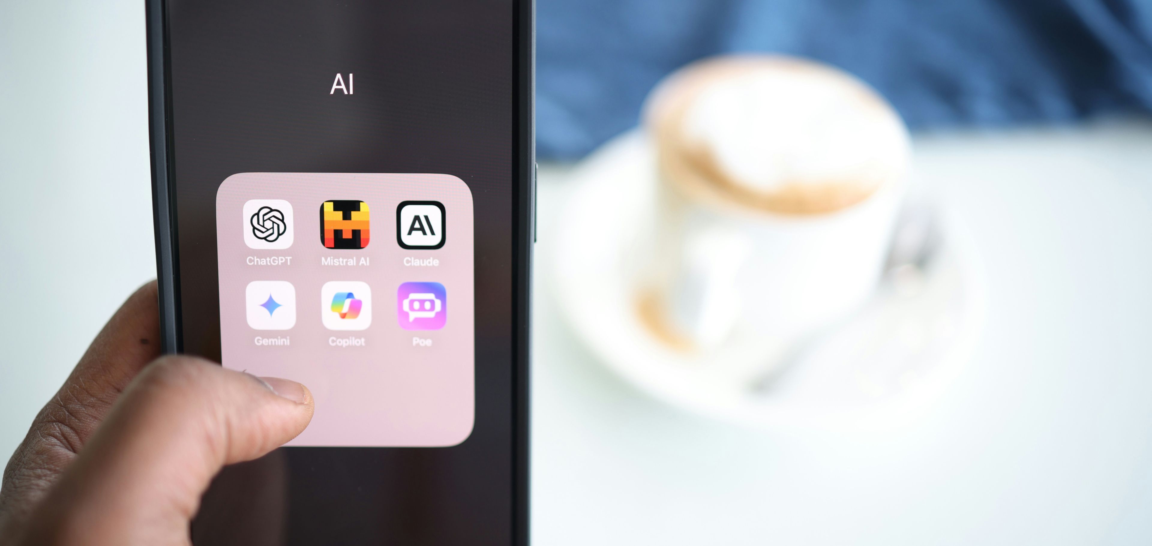 Man holds his phone while drinking coffee. The screen shows AI writing apps.