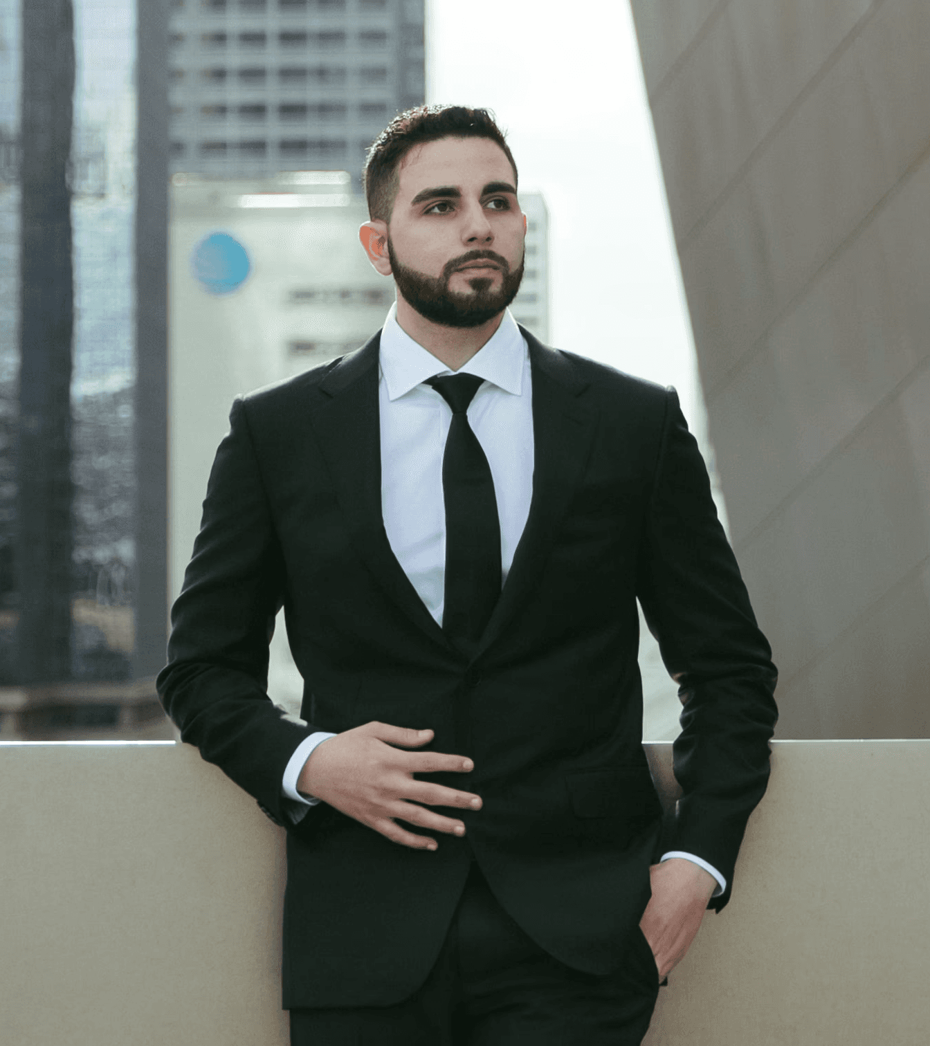 Jon Sargsyan, a founder and partner of The Injury Law Firm, looking off into the distance wearing a suit in front of Los Angeles buildings