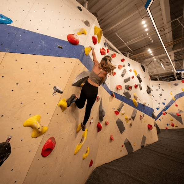 Mar climbing on the wall of an indoor bouldering gym.