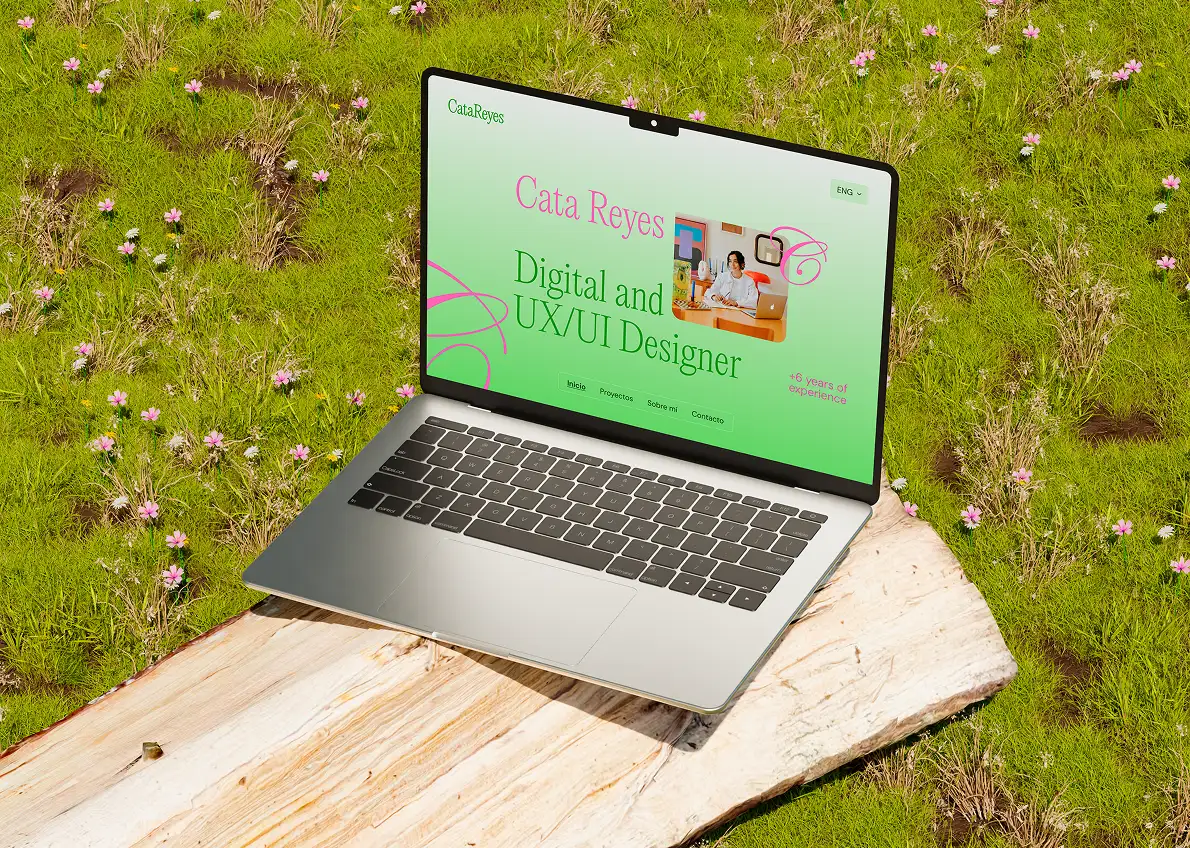 Portada de un portfolio web en notebook sobre Cata Reyes, diseñadora UX/UI, con colores vivos en verde y rosa sobre un fondo natural de césped.