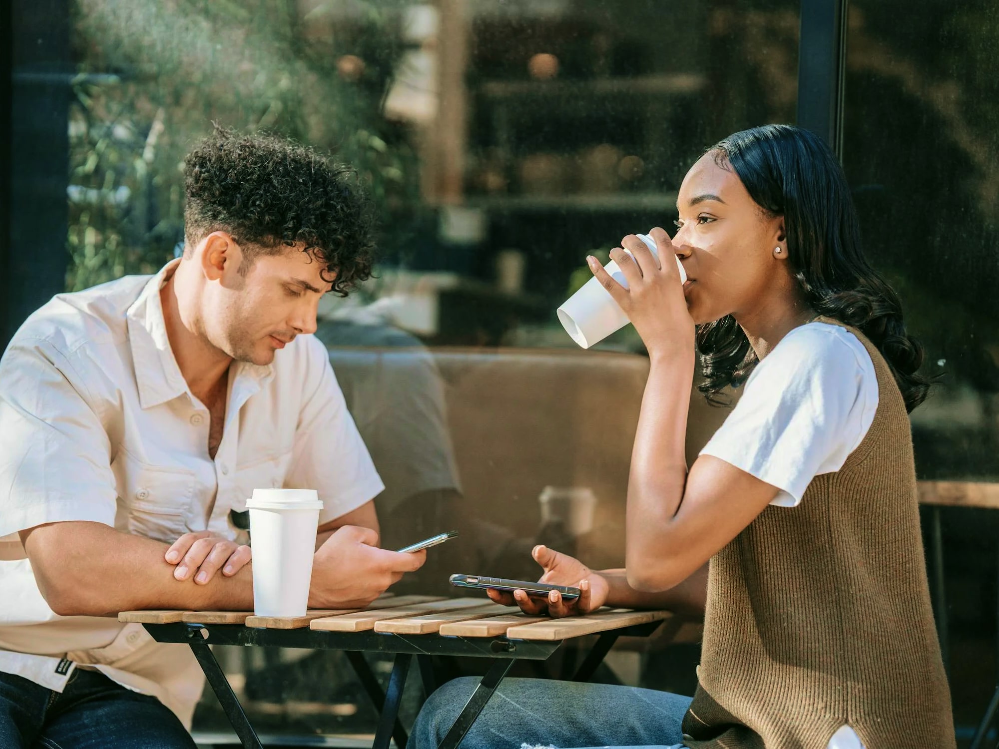 A couple sitting face-to-face outside in a cafe to enjoy the sun