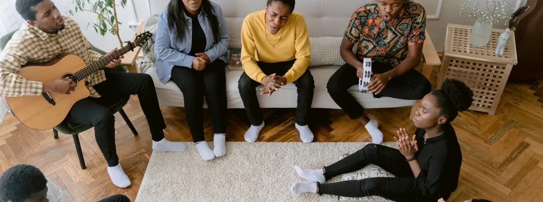 A small group sitting in a circle in a living room with open Bibles