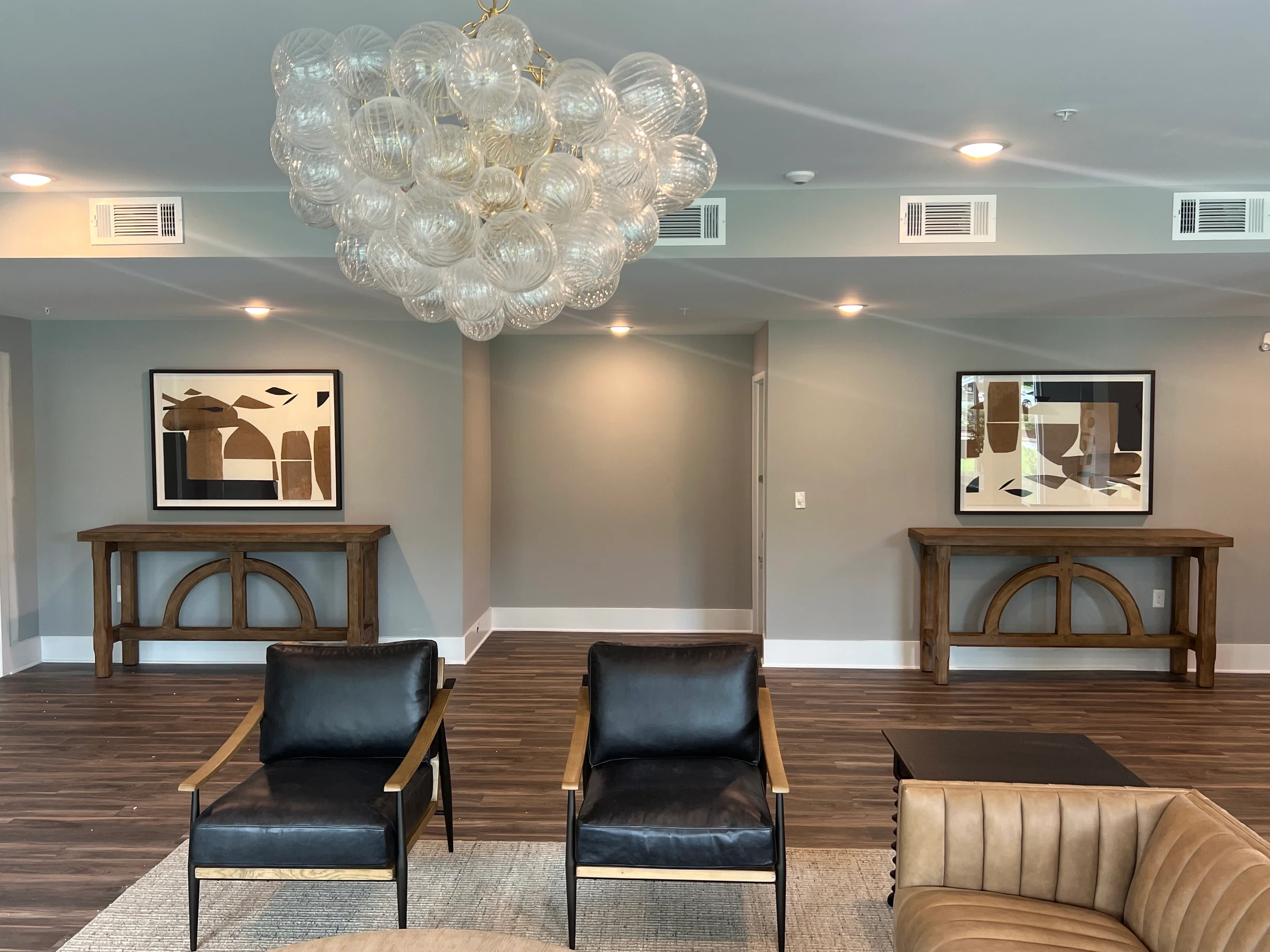 Framed artworks and paired consoles in a furnished lounge.