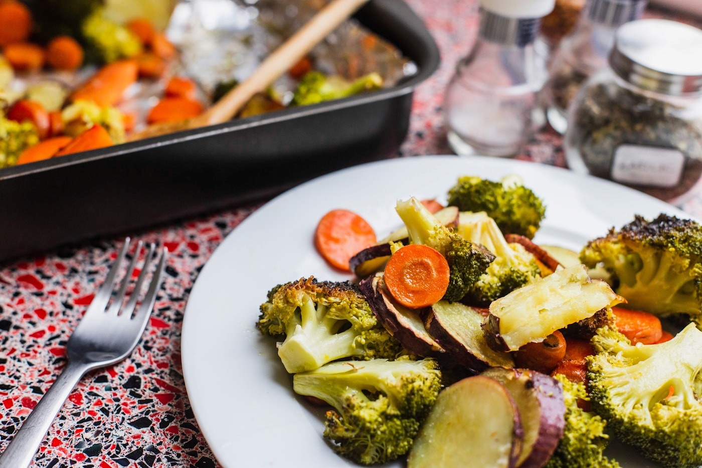 A plate of colorful roasted vegetables including broccoli, carrots and sweet potato, an example of an anti-inflammatory, nutrient-dense meal
