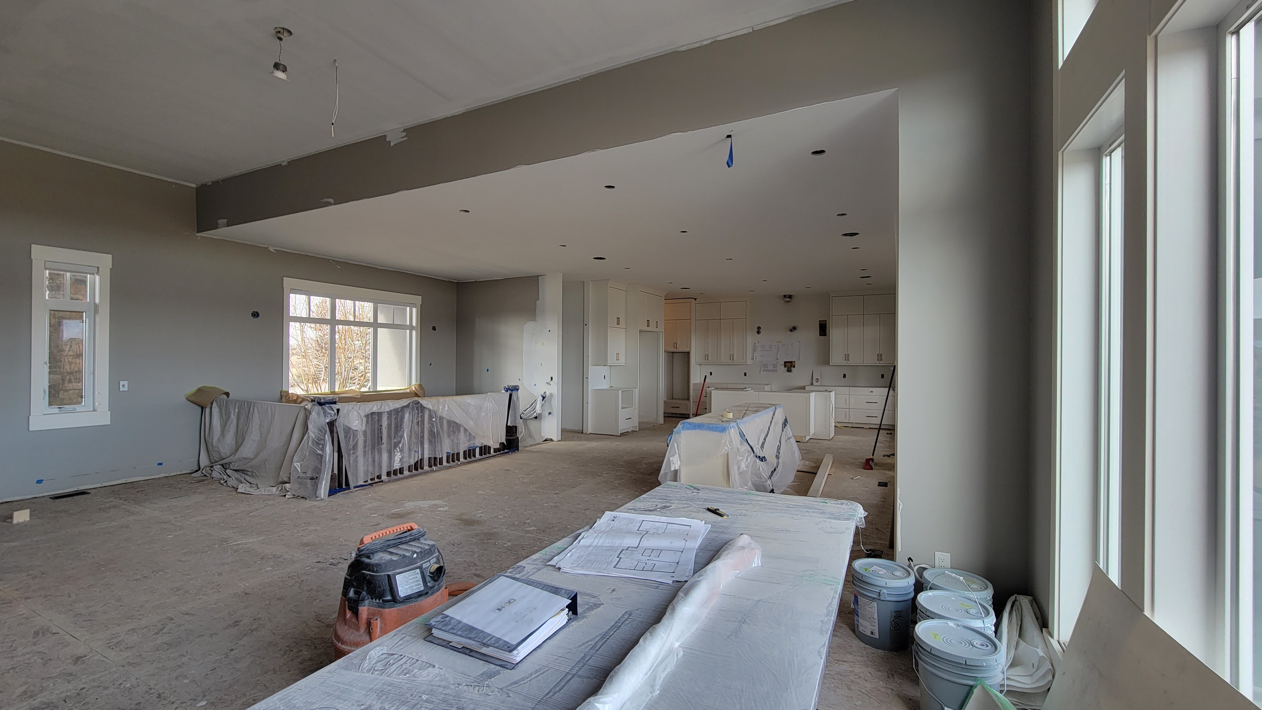 Image of KHD Homes construction site with layout design plans on a table amidst kitchen and interior design elements.