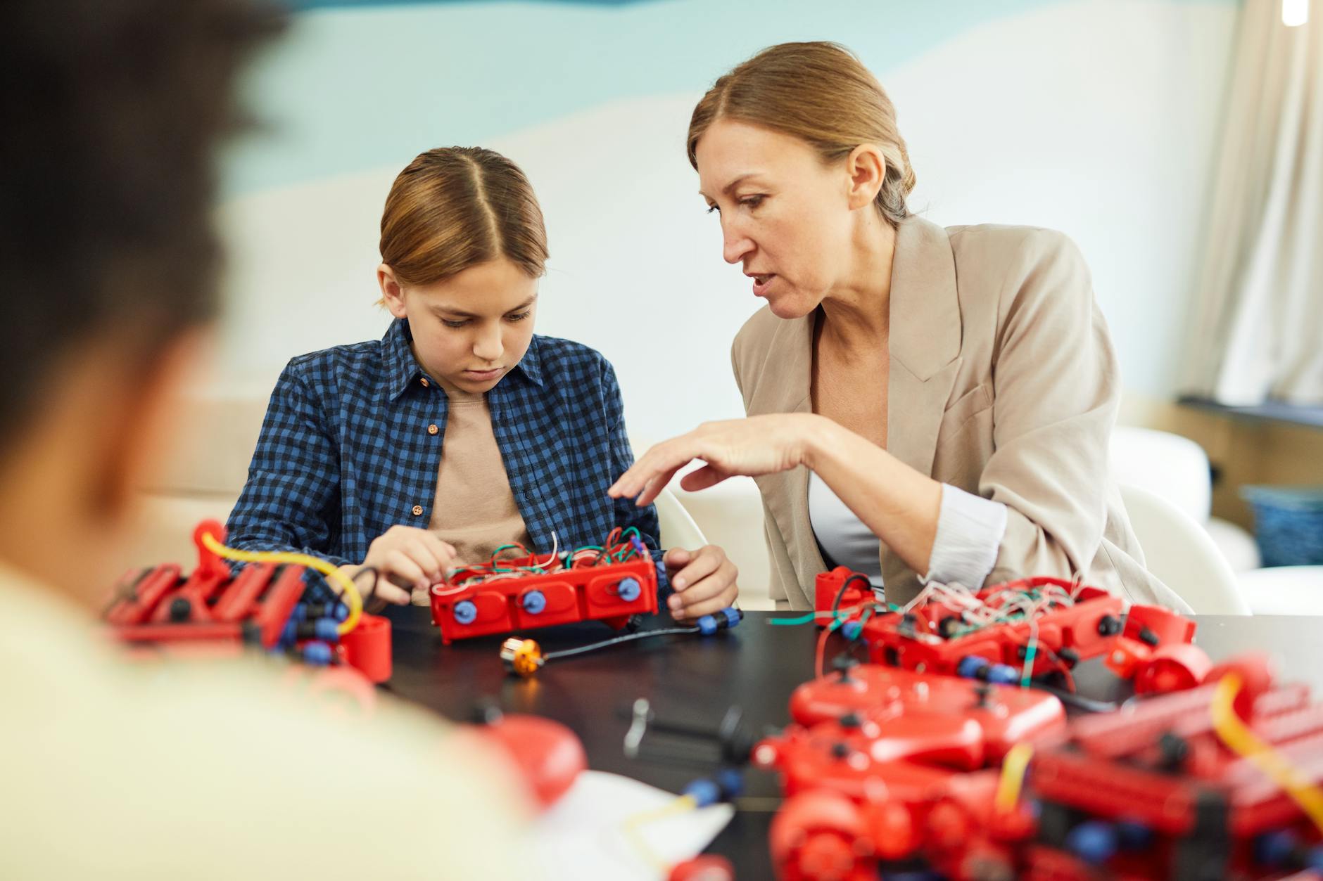 A close-up of a student's hands assembling a programmable robot with gears and wires during a STEM workshop.