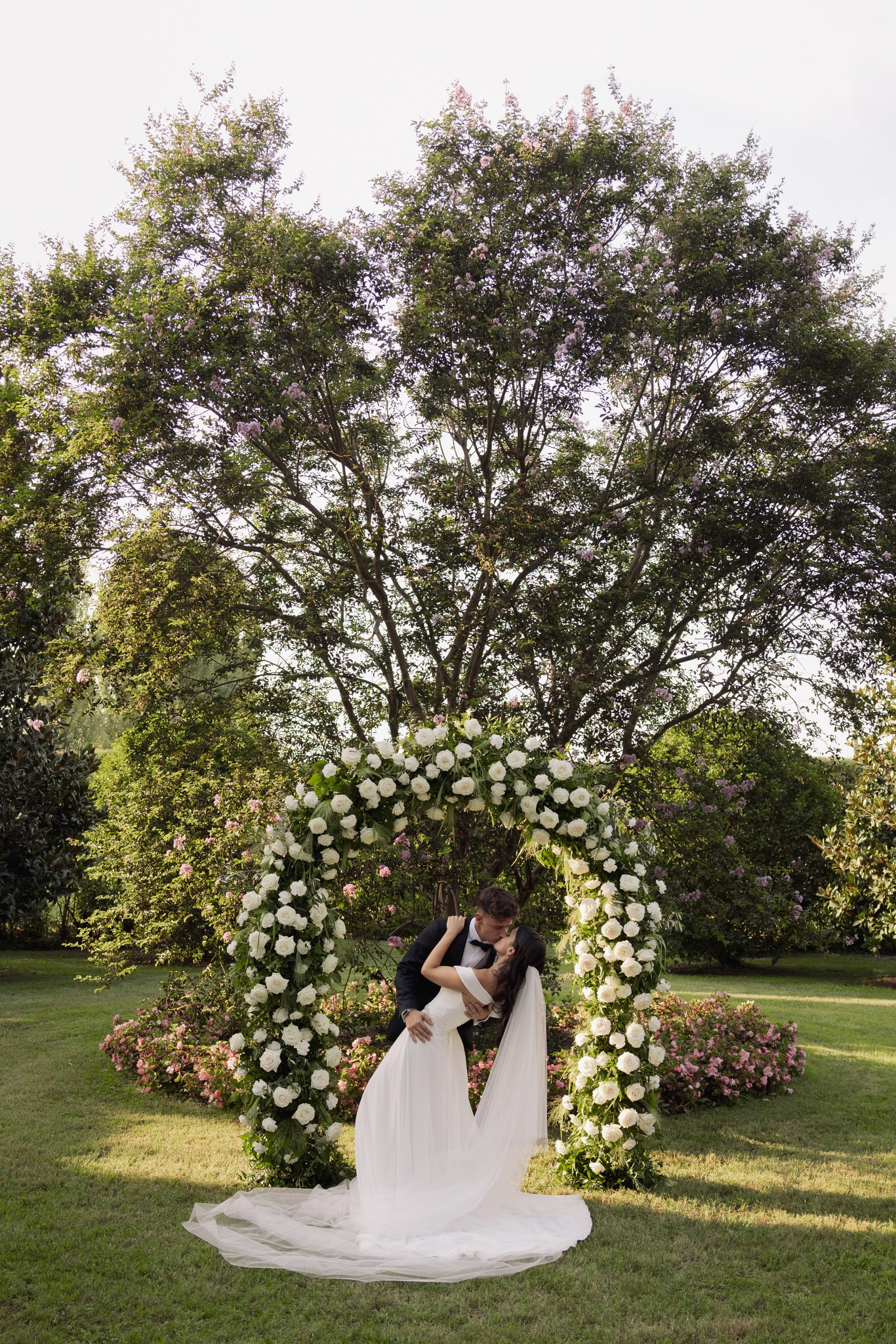 Sposa in abito bianco sotto arco floreale di rose bianche nel giardino di Villa Negri, reportage matrimoniale Fotolize