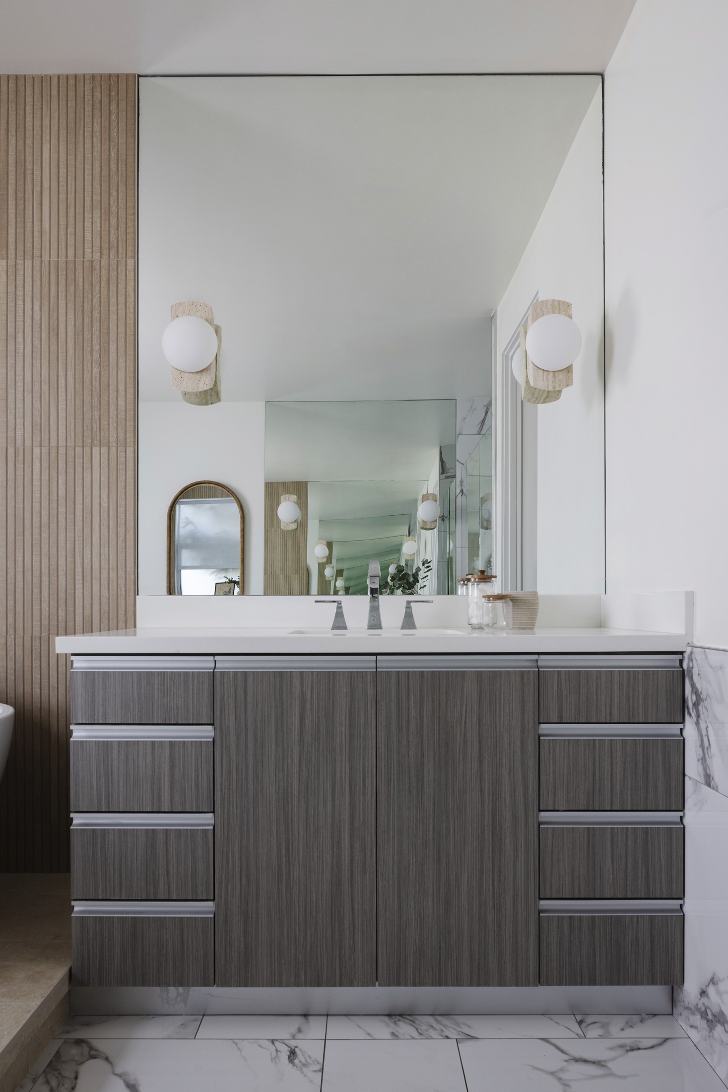 View of bathroom vanity with sconce lighting and wood accent wall