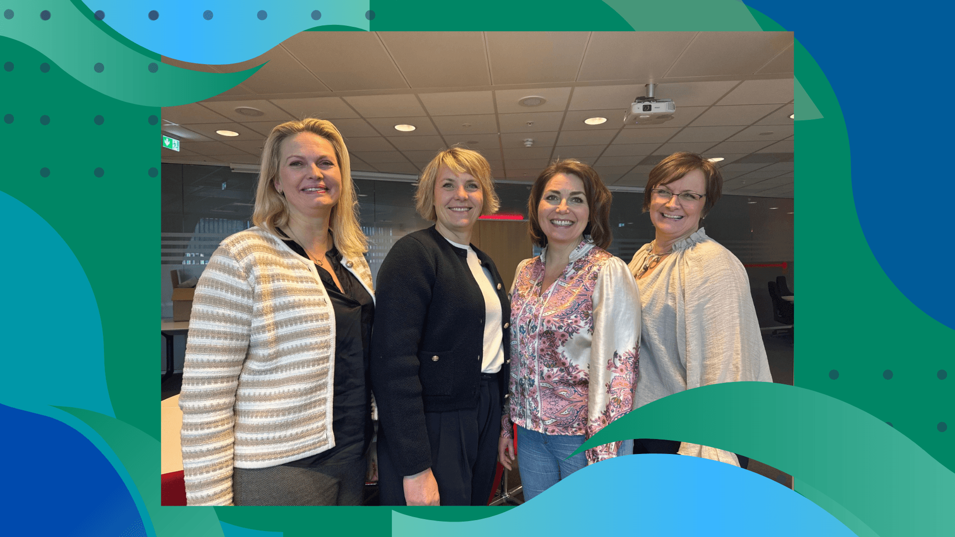 Four people posing together at an indoor event, smiling and dressed in casual attire.