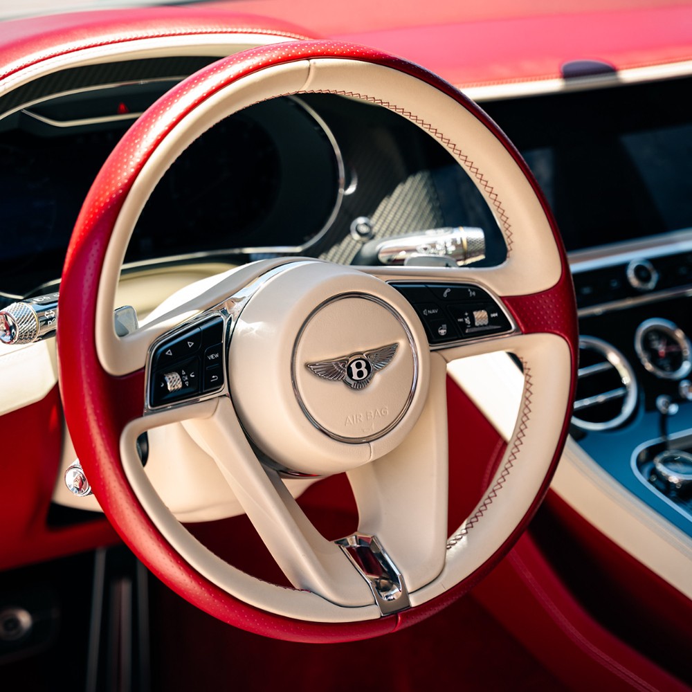 Bentley Continental GT interior showing red and white leather steering wheel and digital dash