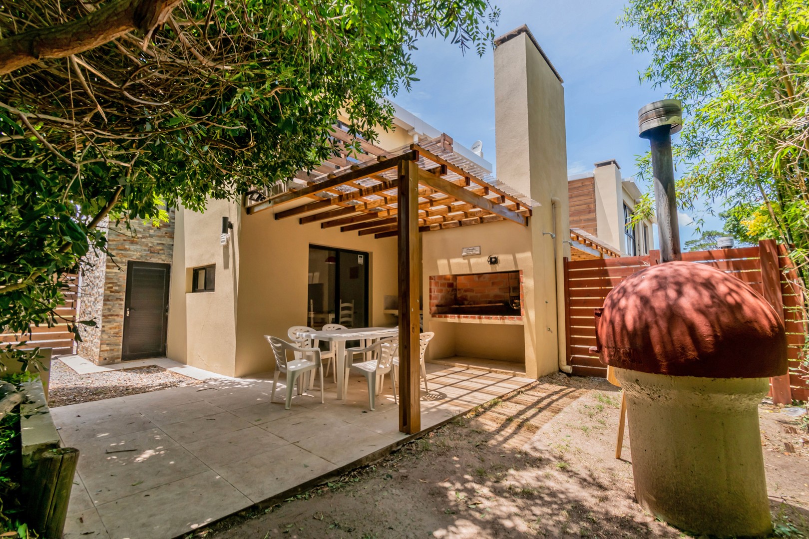 Patio trasero techado de Casa Albatros con parrillero y mesa de comedor - área techada que combina comodidad y funcionalidad para disfrutar de asados.