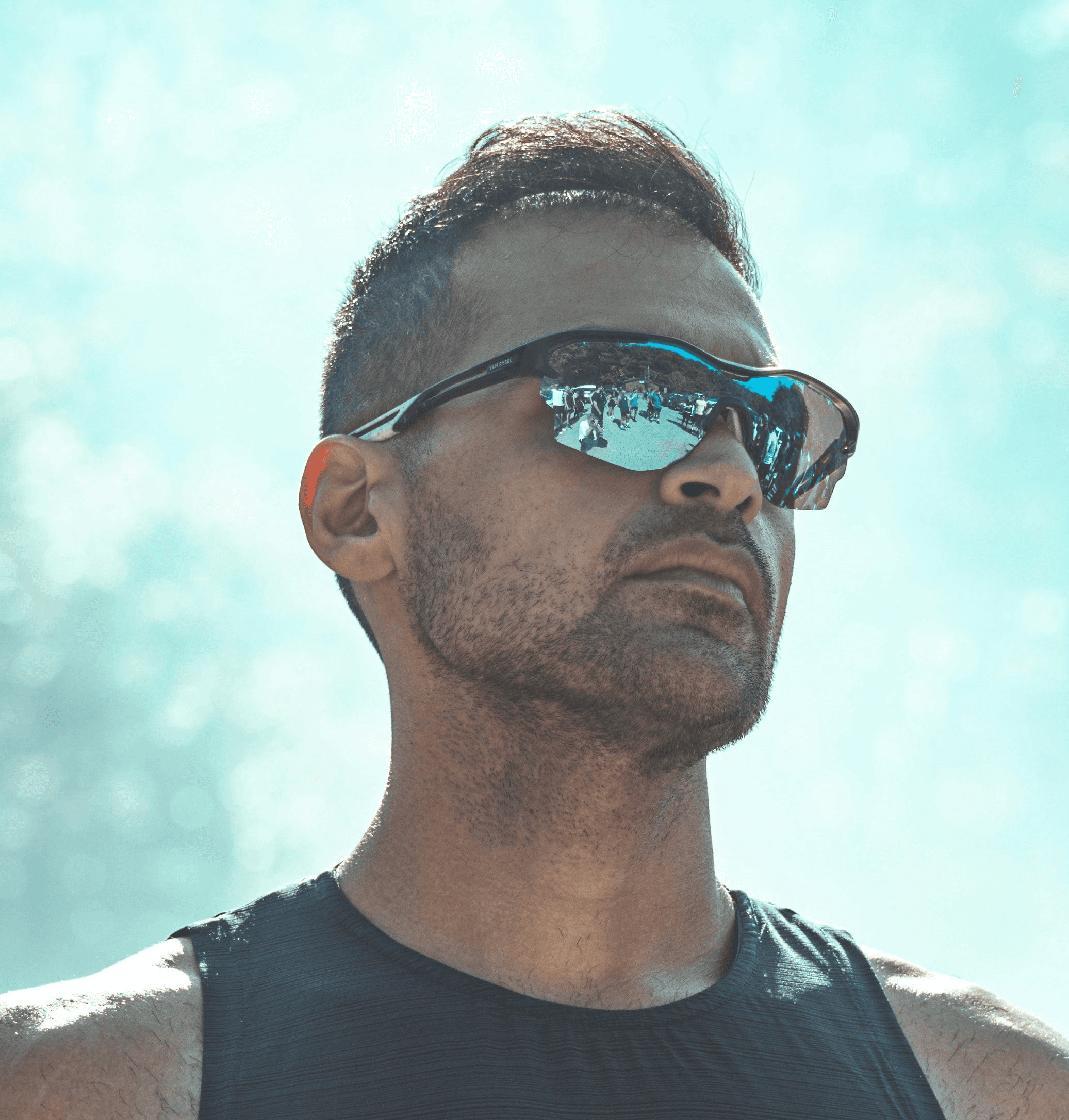 a man in a tank top and sunglasses standing in front of a group of people